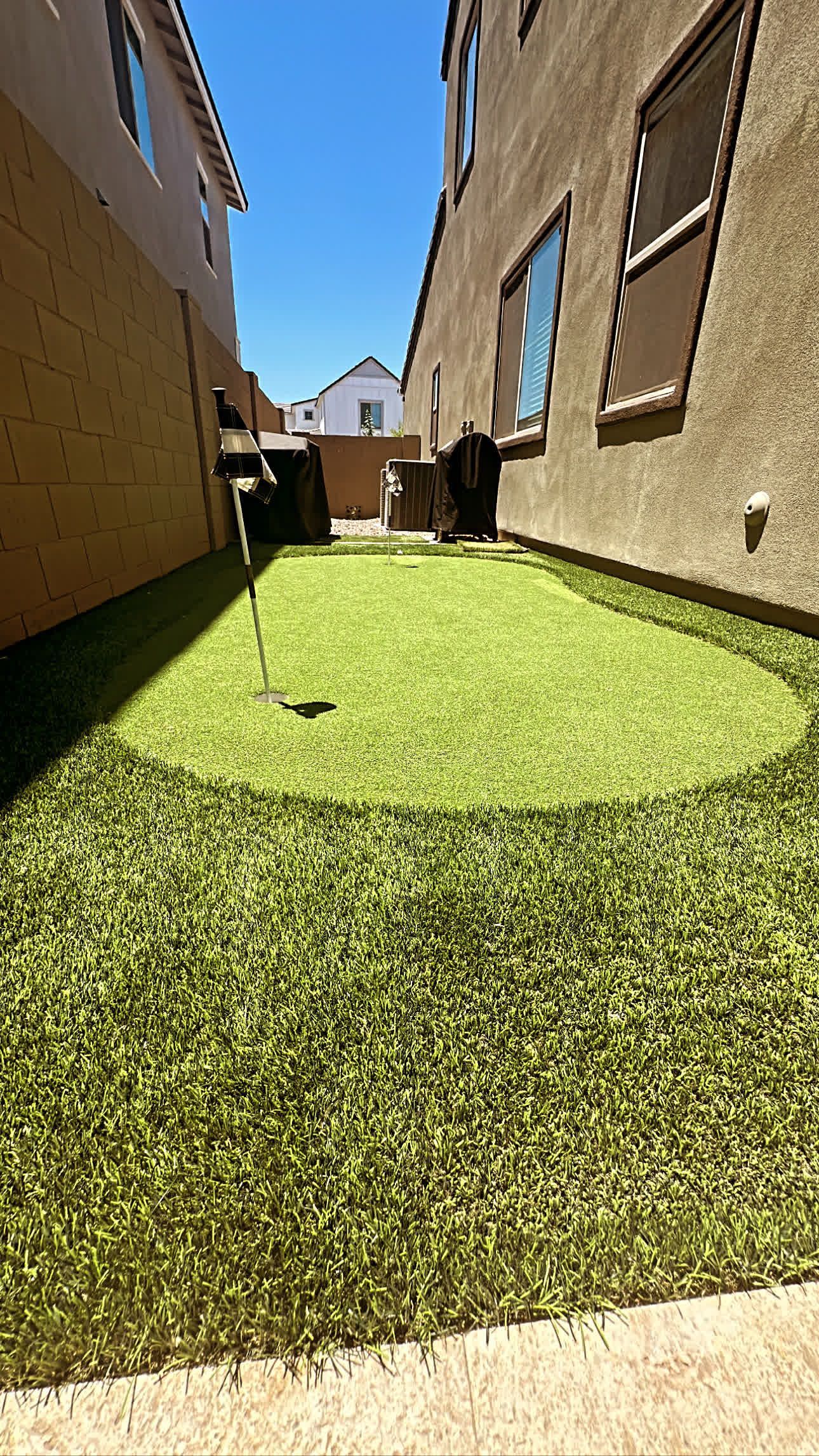 There is a putting green in the backyard of a house.