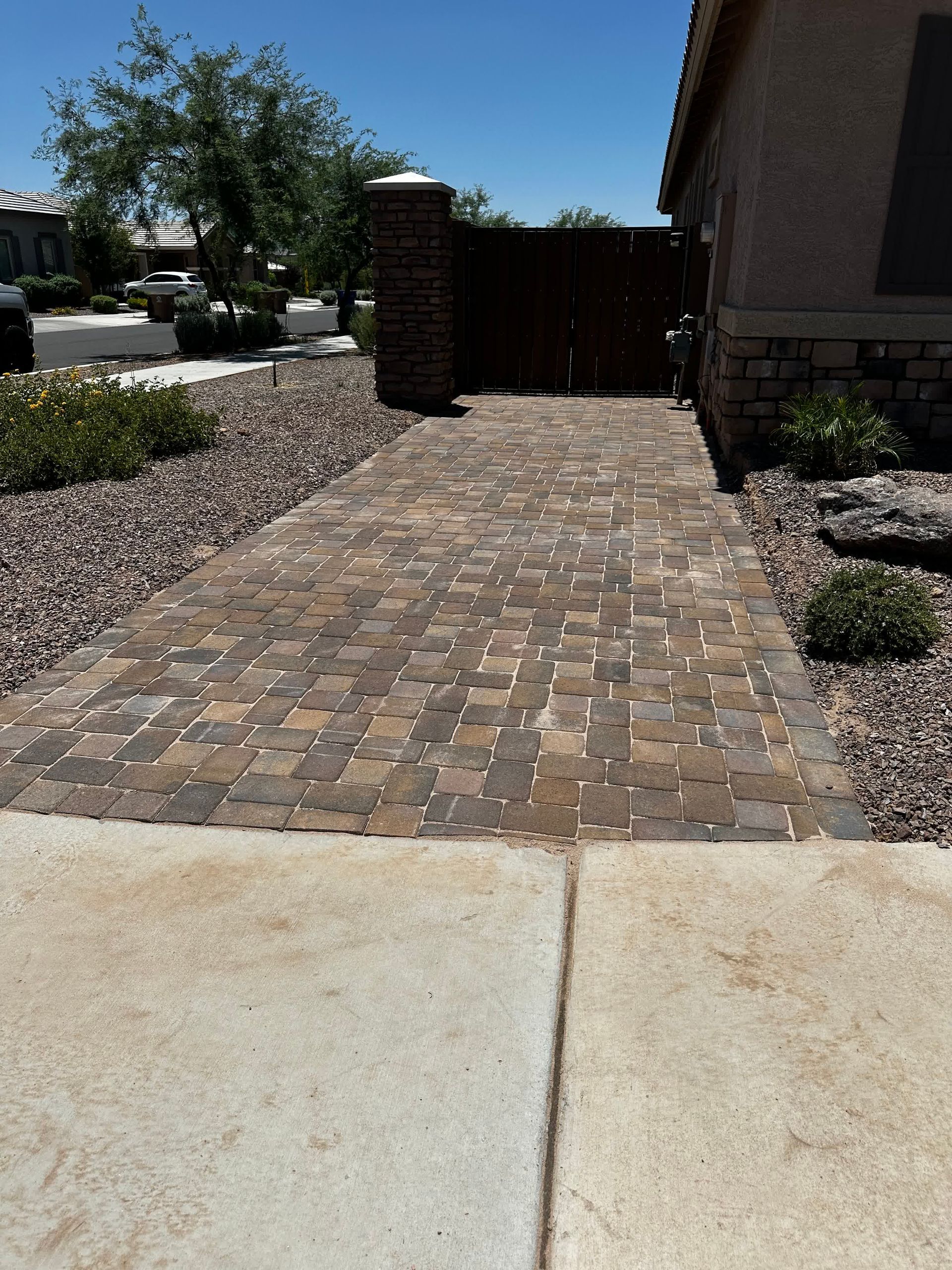 A driveway with bricks and gravel leading to a house