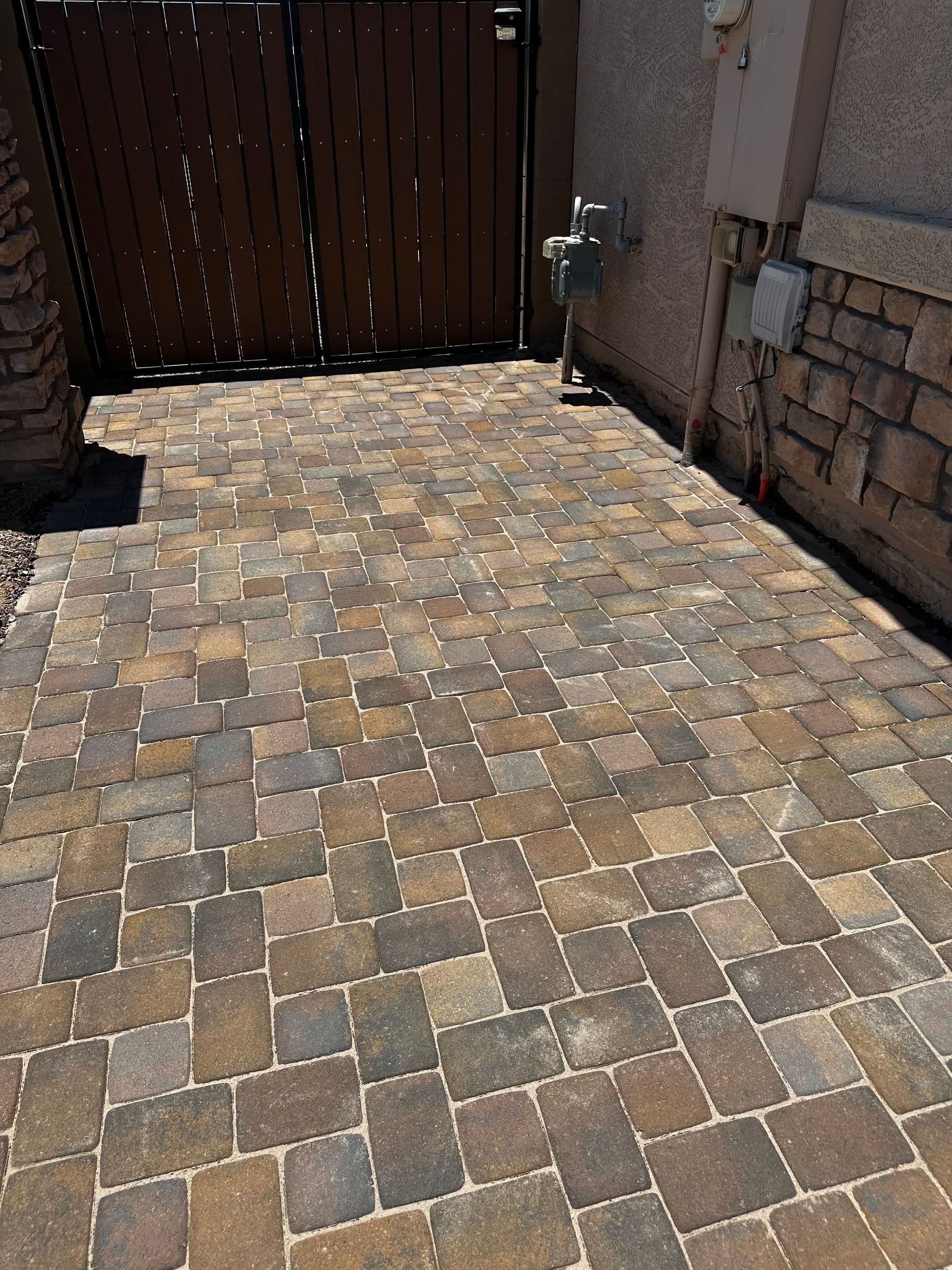 A brick walkway with a wooden gate in the background.