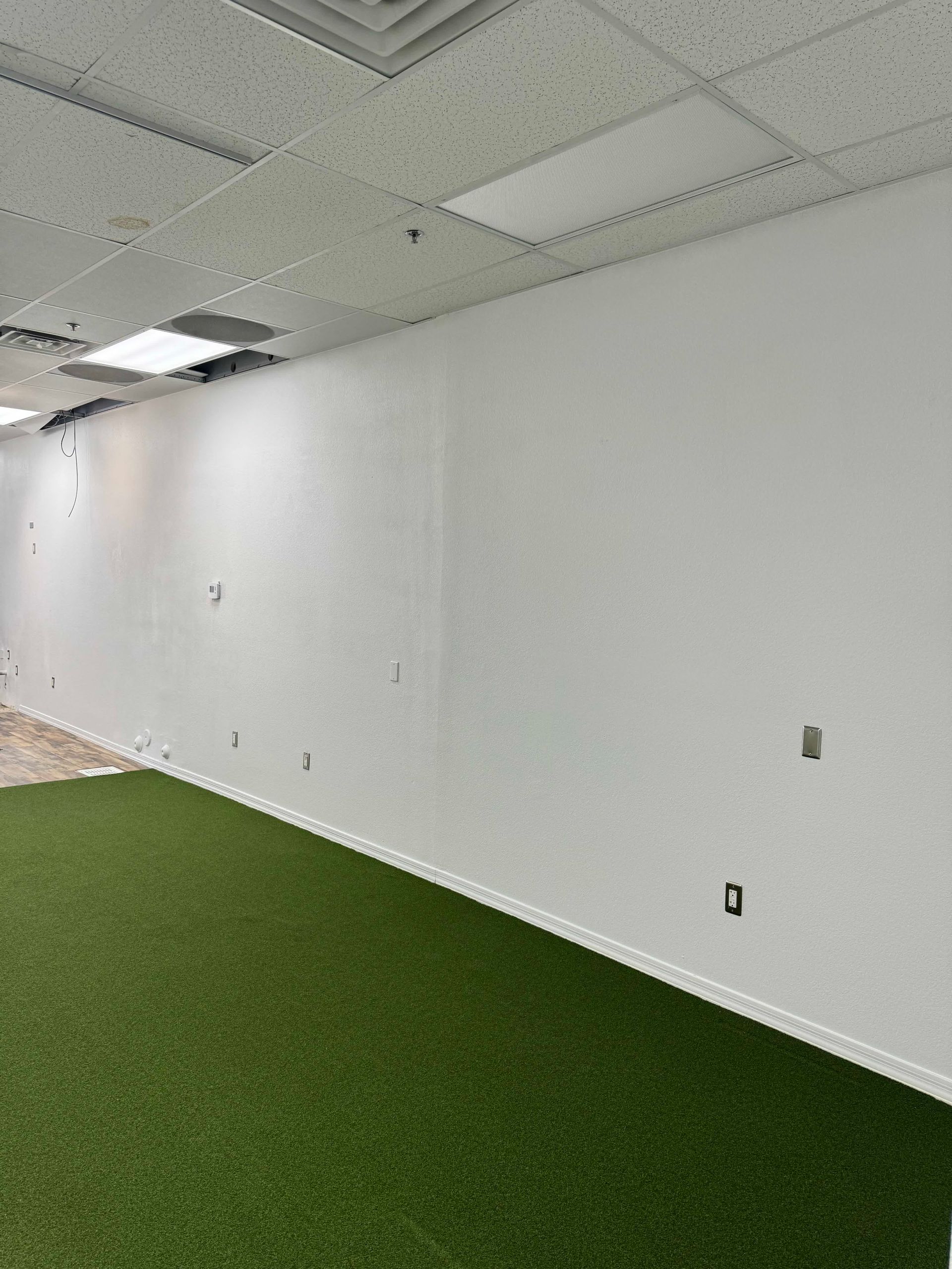 An empty room with a green carpet and white walls.