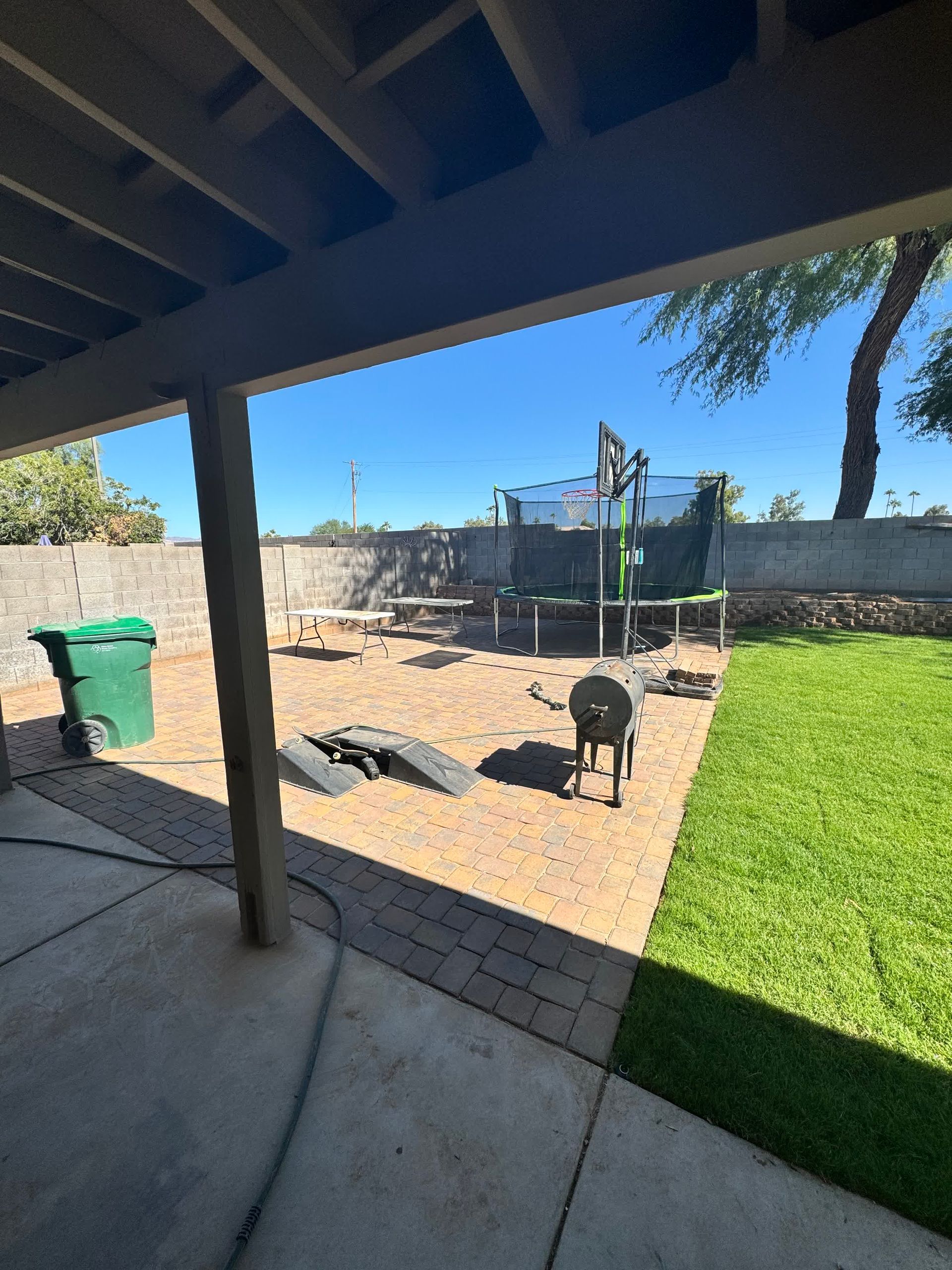 A backyard with a trampoline and a green trash can