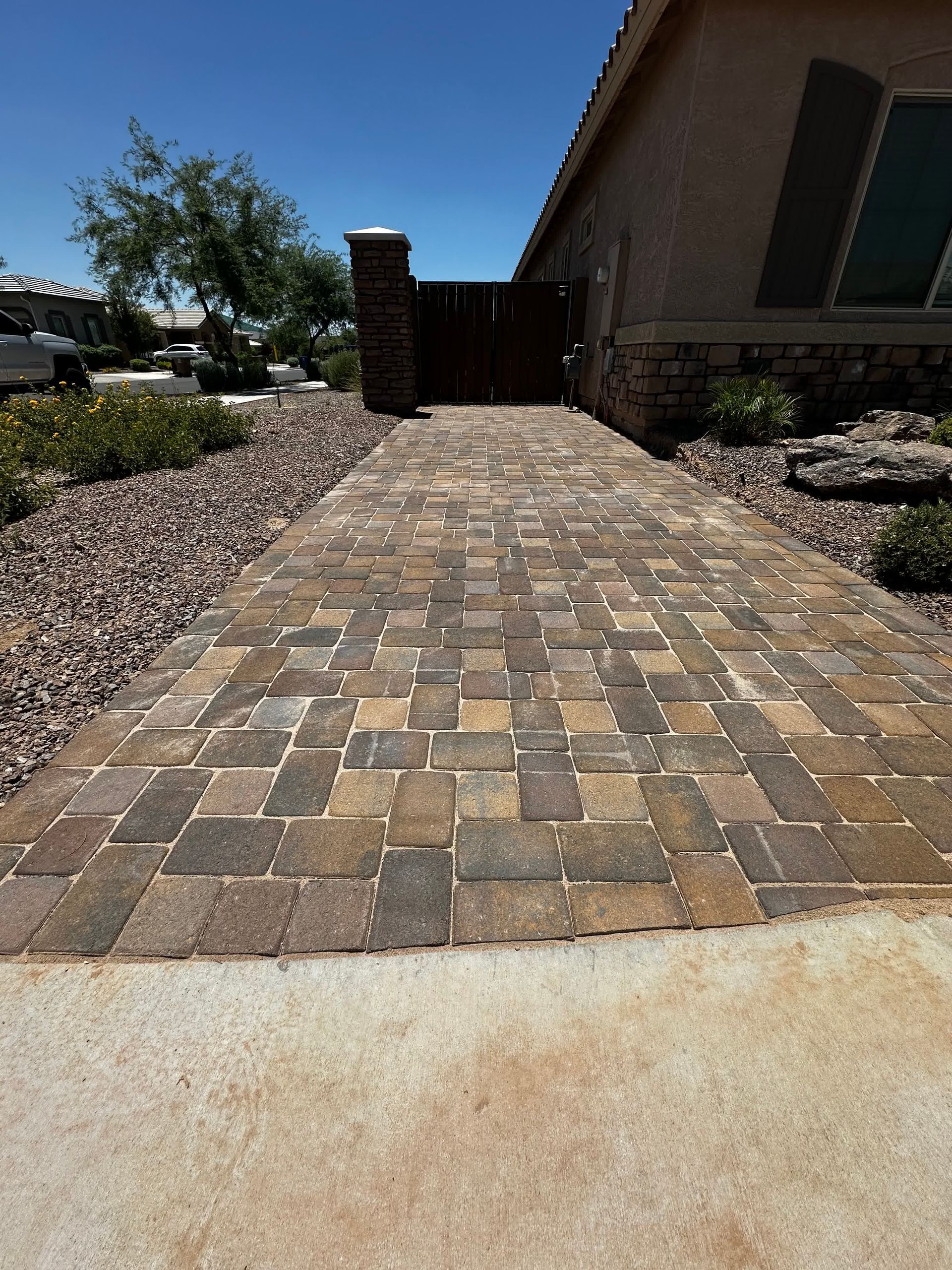 A brick walkway leading to a house on a sunny day