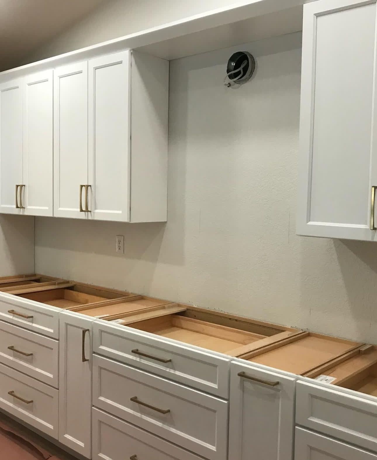 A kitchen with a lot of white cabinets and drawers