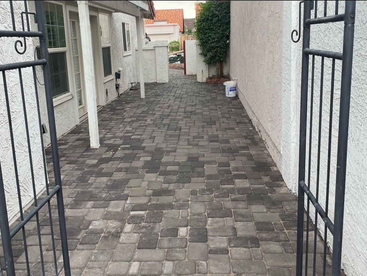 A brick walkway leading to a house with a gate.