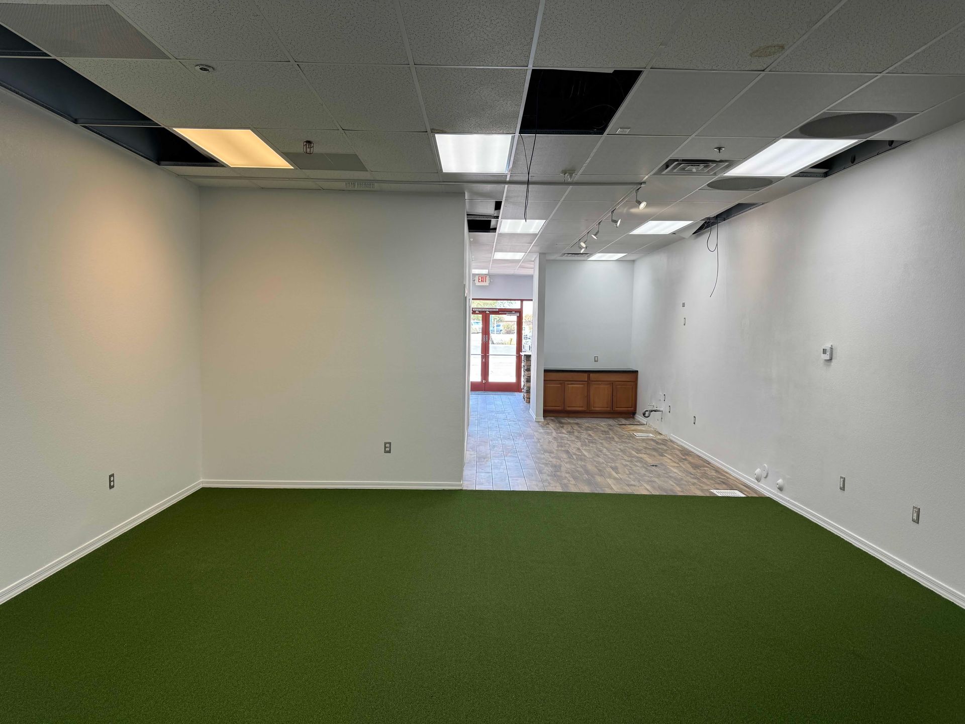 An empty room with a green carpet and white walls.
