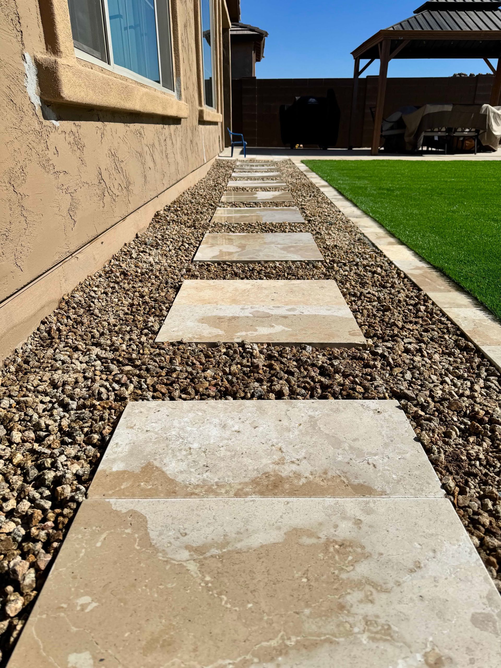 A stone walkway leading to a house with a gazebo in the background