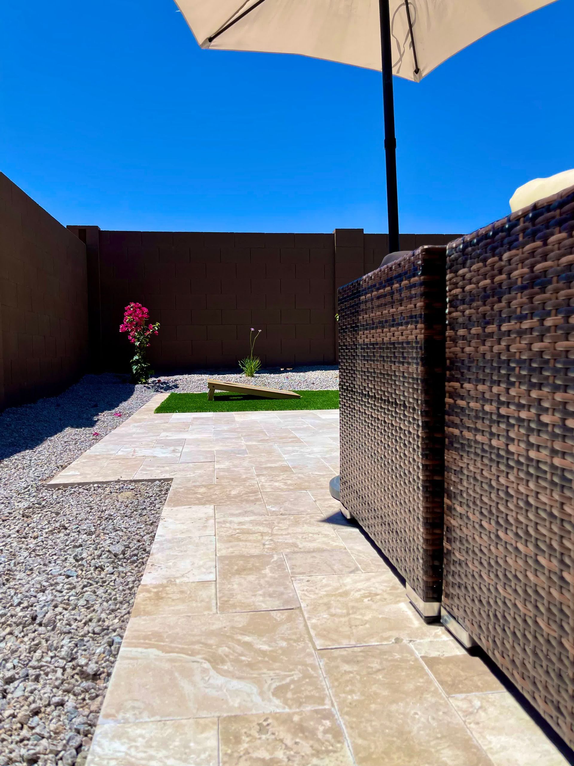 A patio with wicker furniture and an umbrella on a sunny day