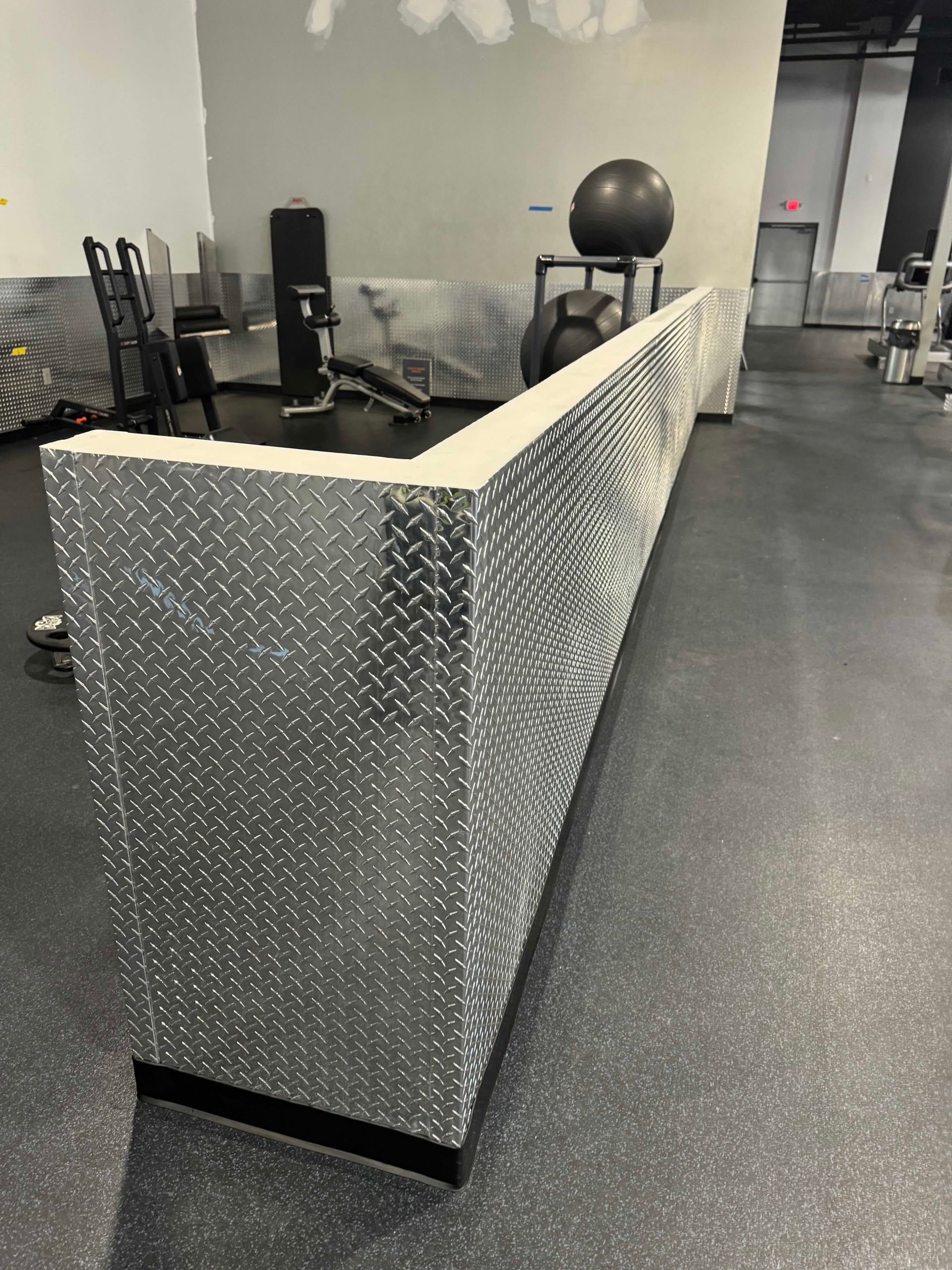 A long silver counter in a gym with a treadmill in the background