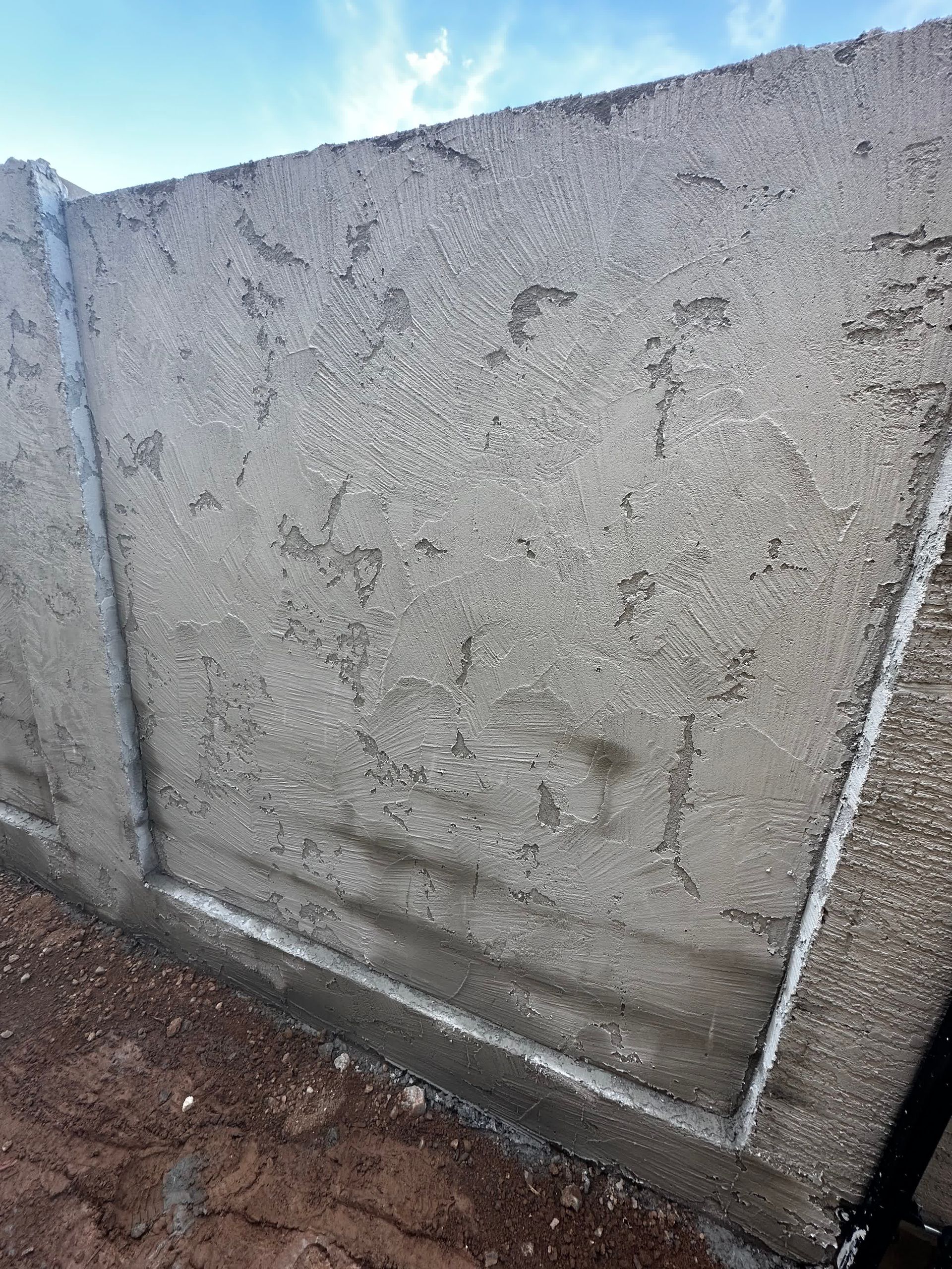 A close up of a concrete wall with a blue sky in the background.