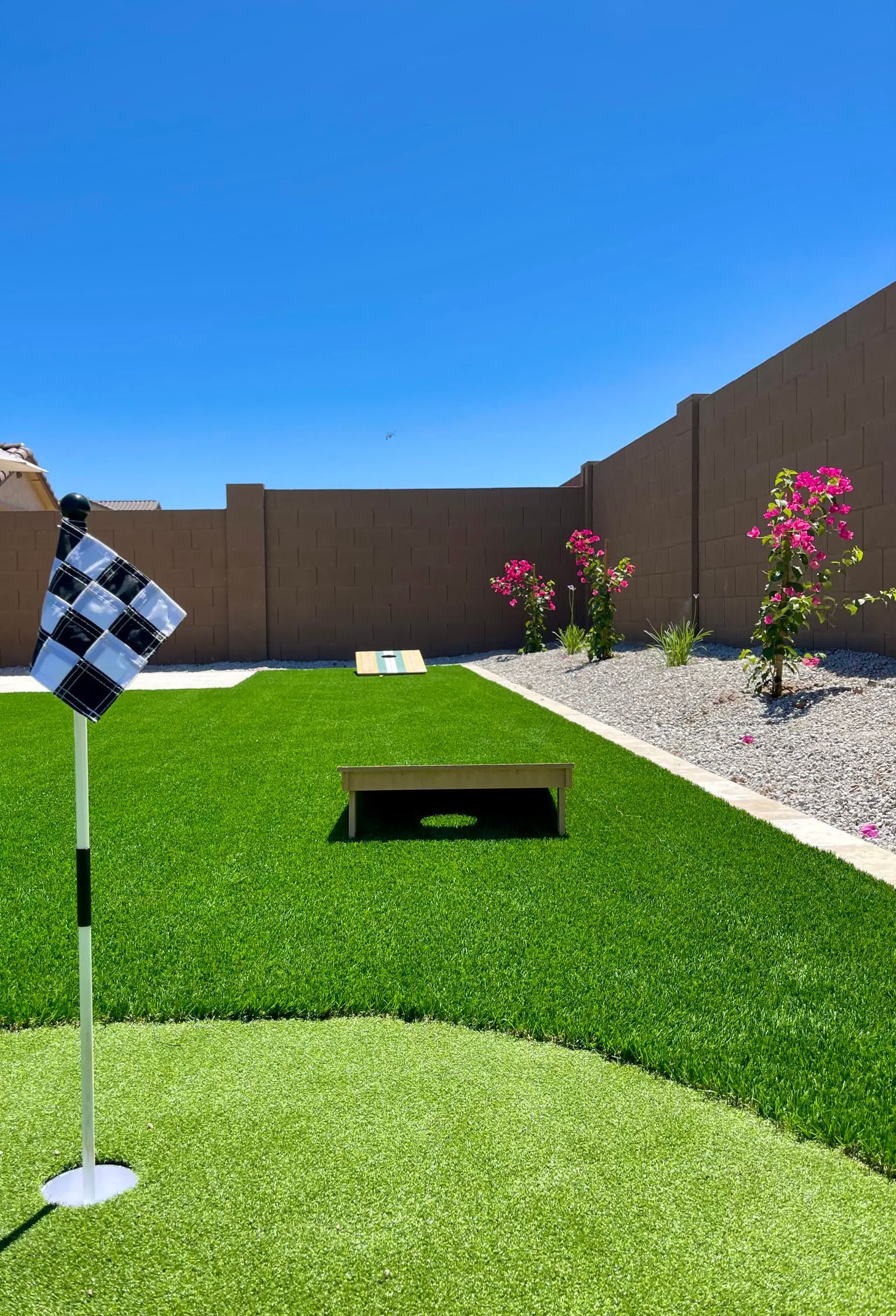 A backyard with a putting green and a bag toss game.
