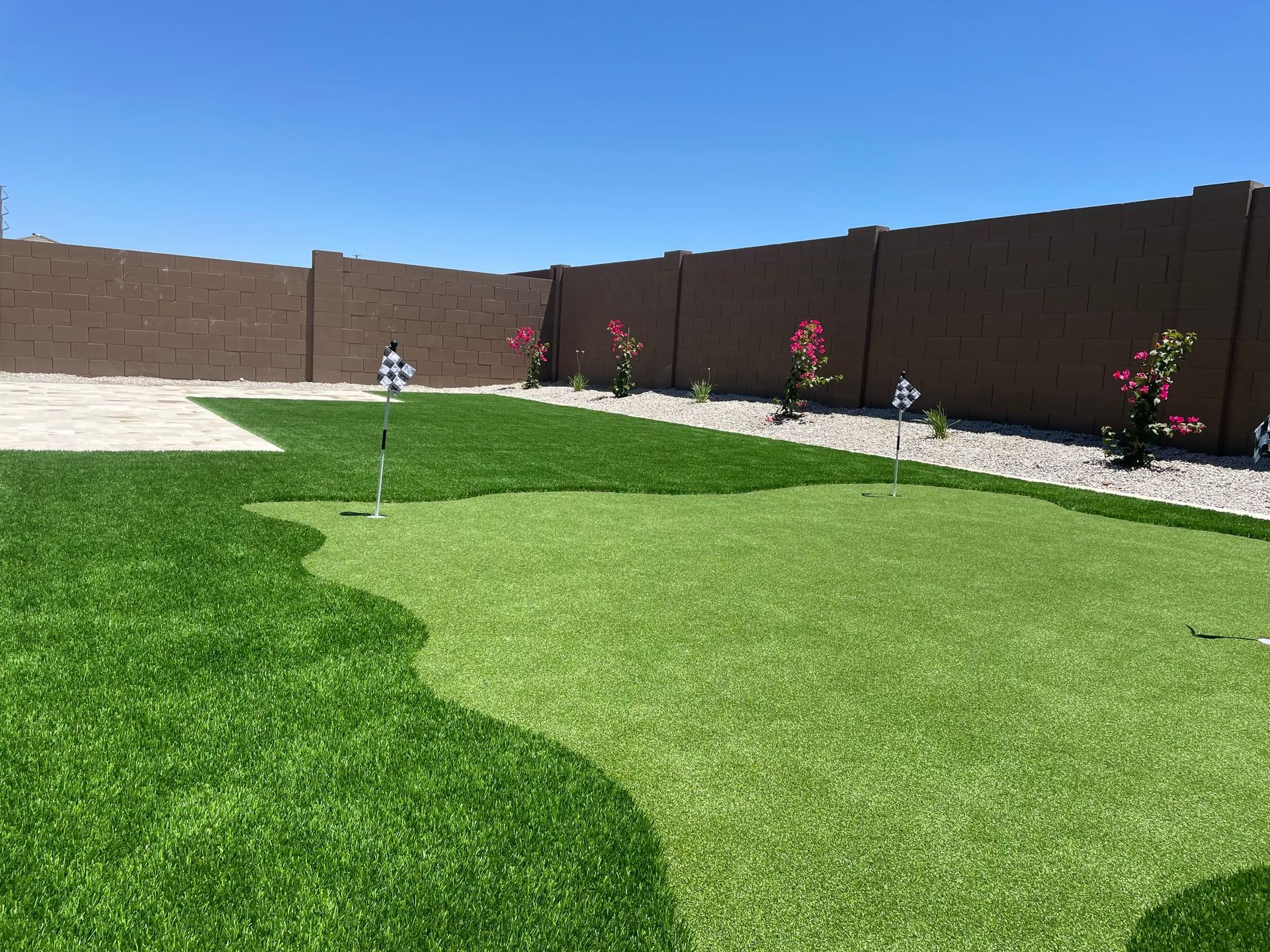 A backyard with a putting green and a fence.