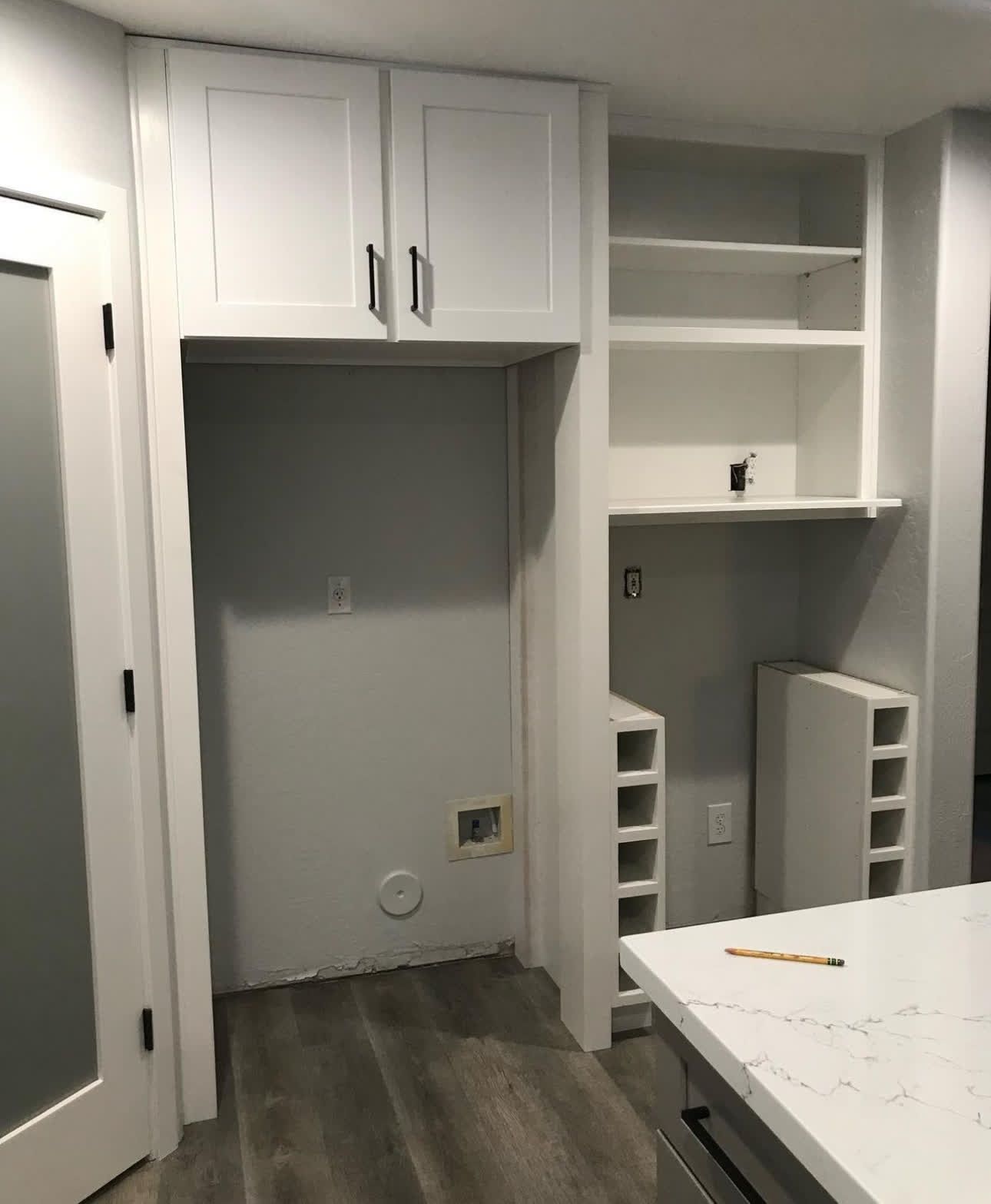A kitchen with white cabinets and a pencil on the counter.