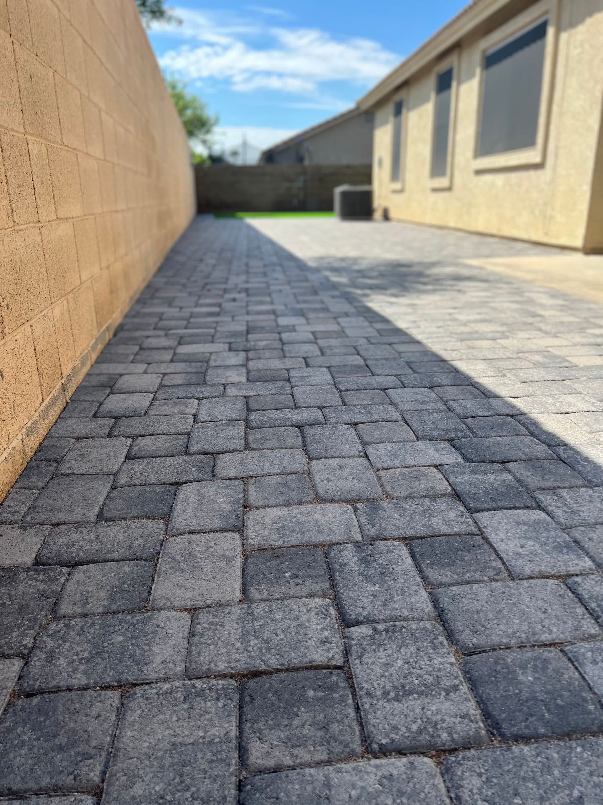 A brick walkway leading to a house on a sunny day