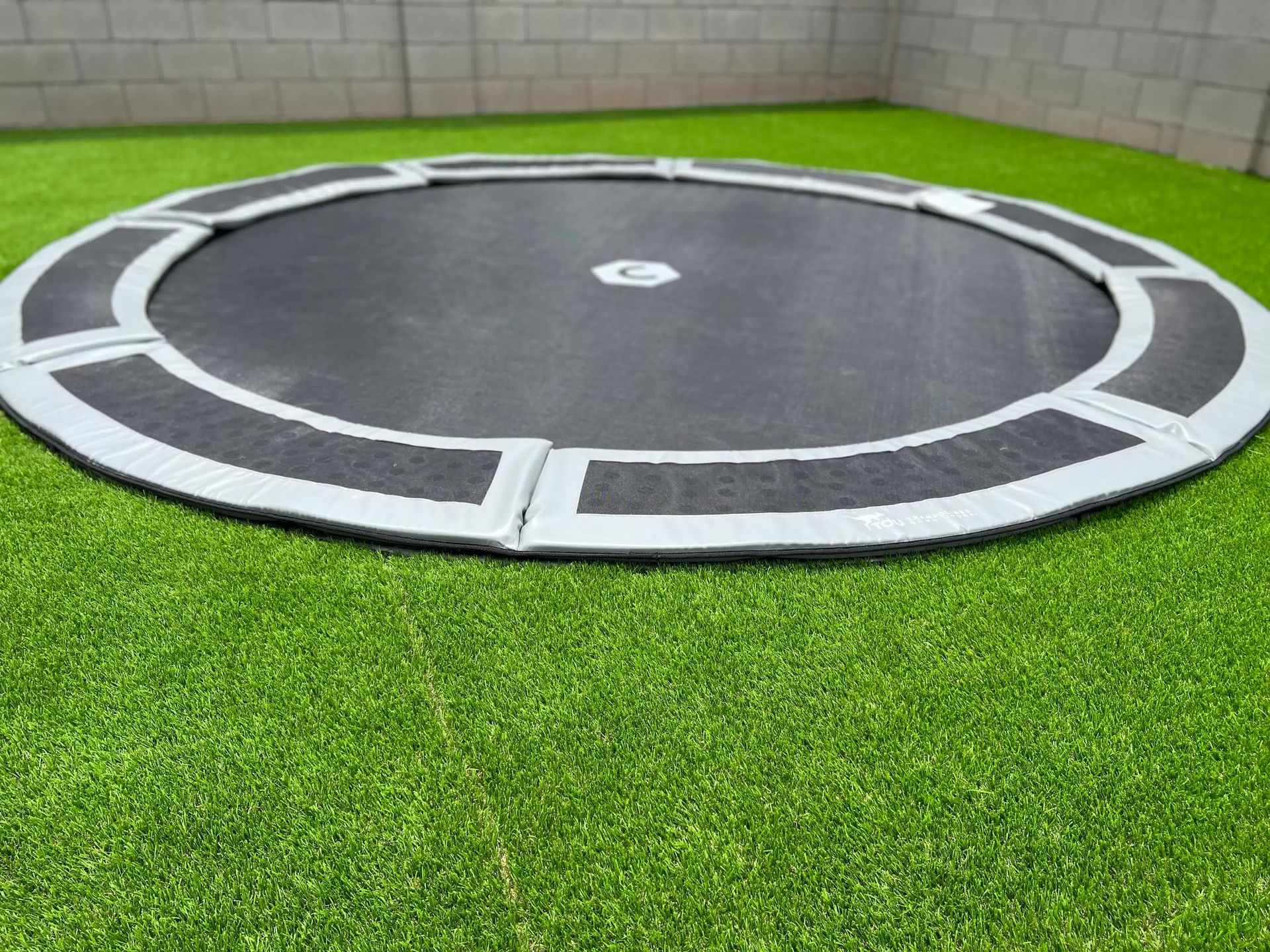 A round trampoline is sitting on top of a lush green lawn.