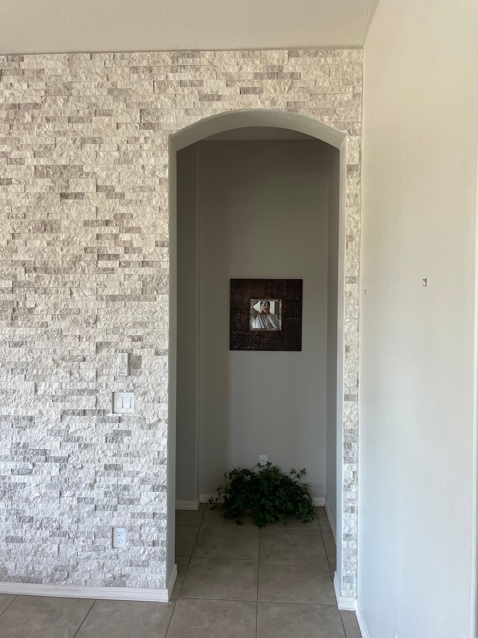 A hallway with a brick wall and a picture on the wall.