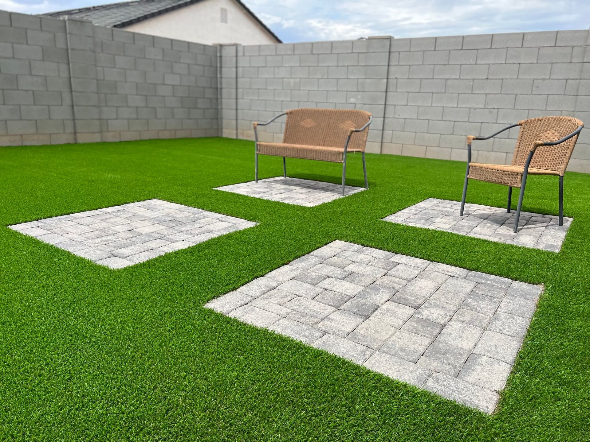 A backyard with a bench and chairs and a brick wall.