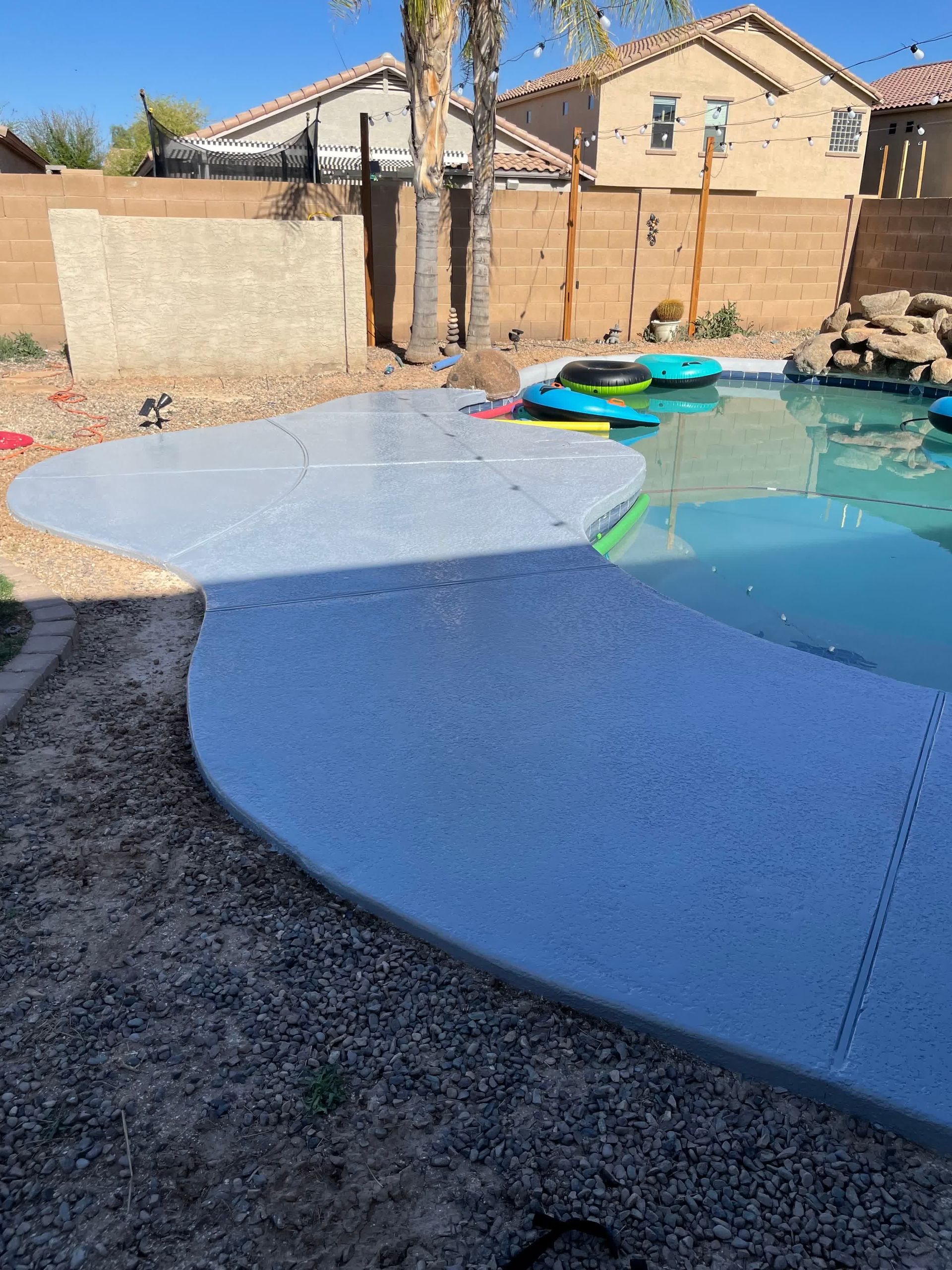 A swimming pool with a concrete patio in front of it.
