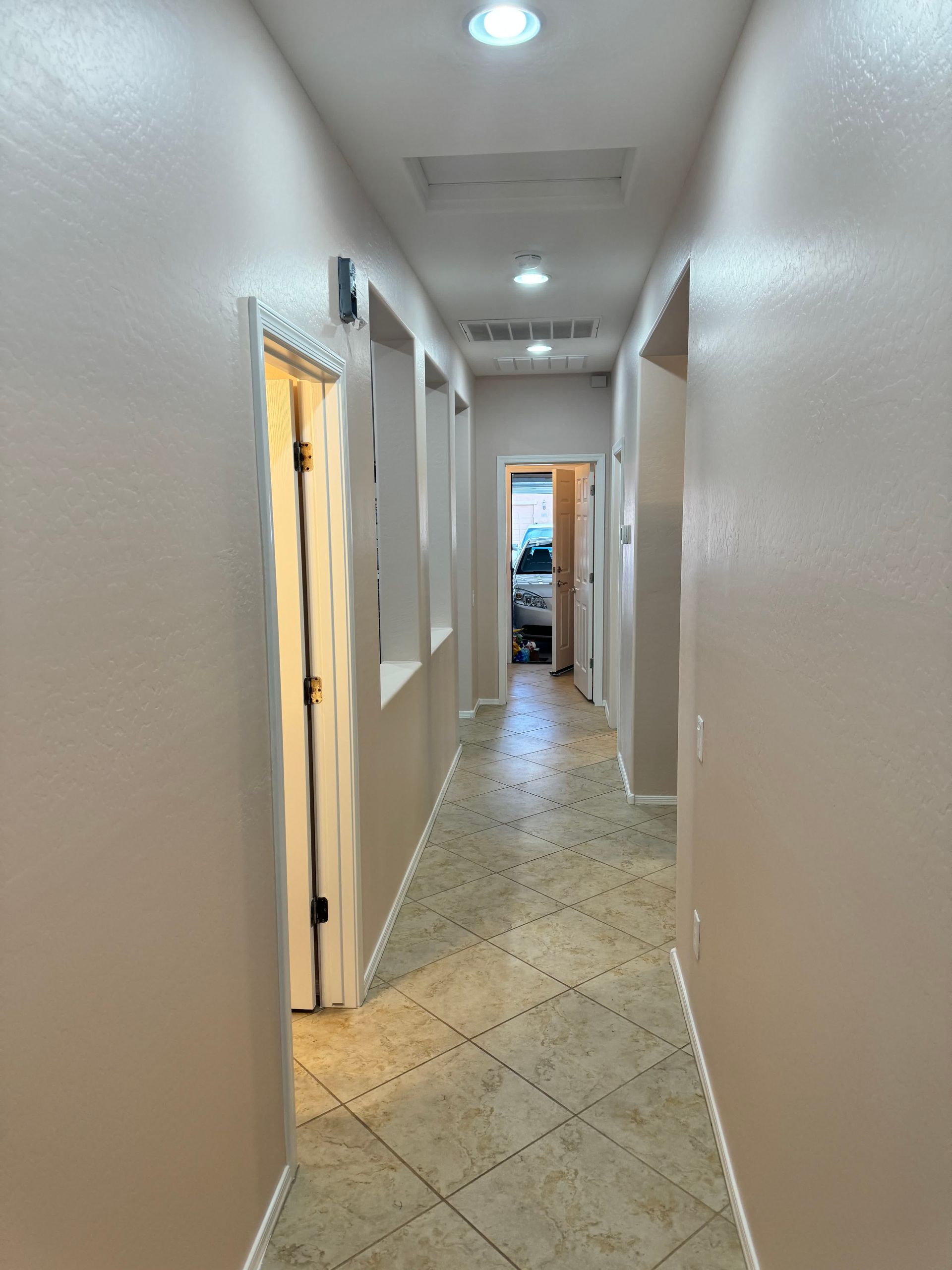 A long hallway with tan walls and tile floors