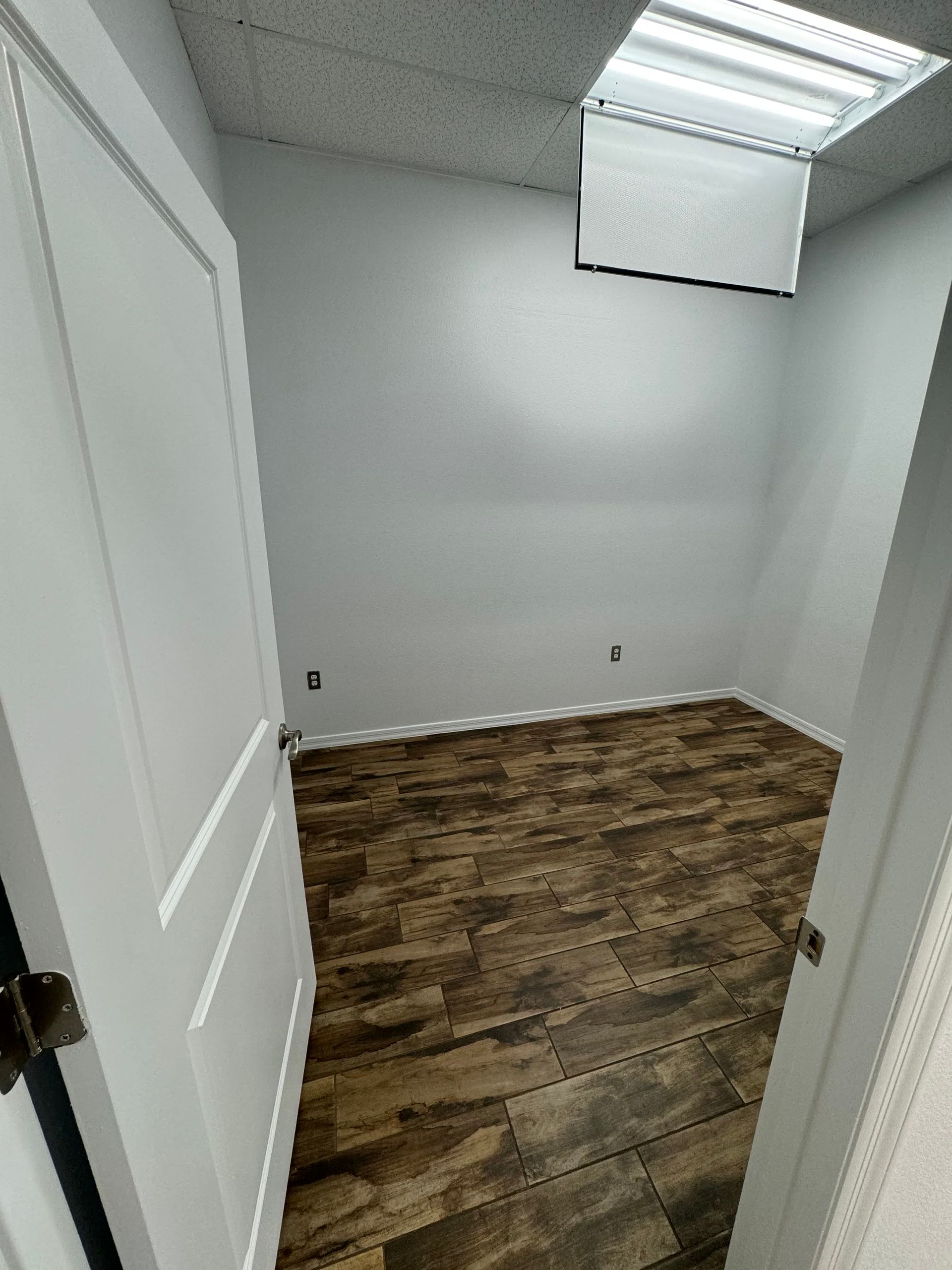 An empty room with a wooden floor and white walls.