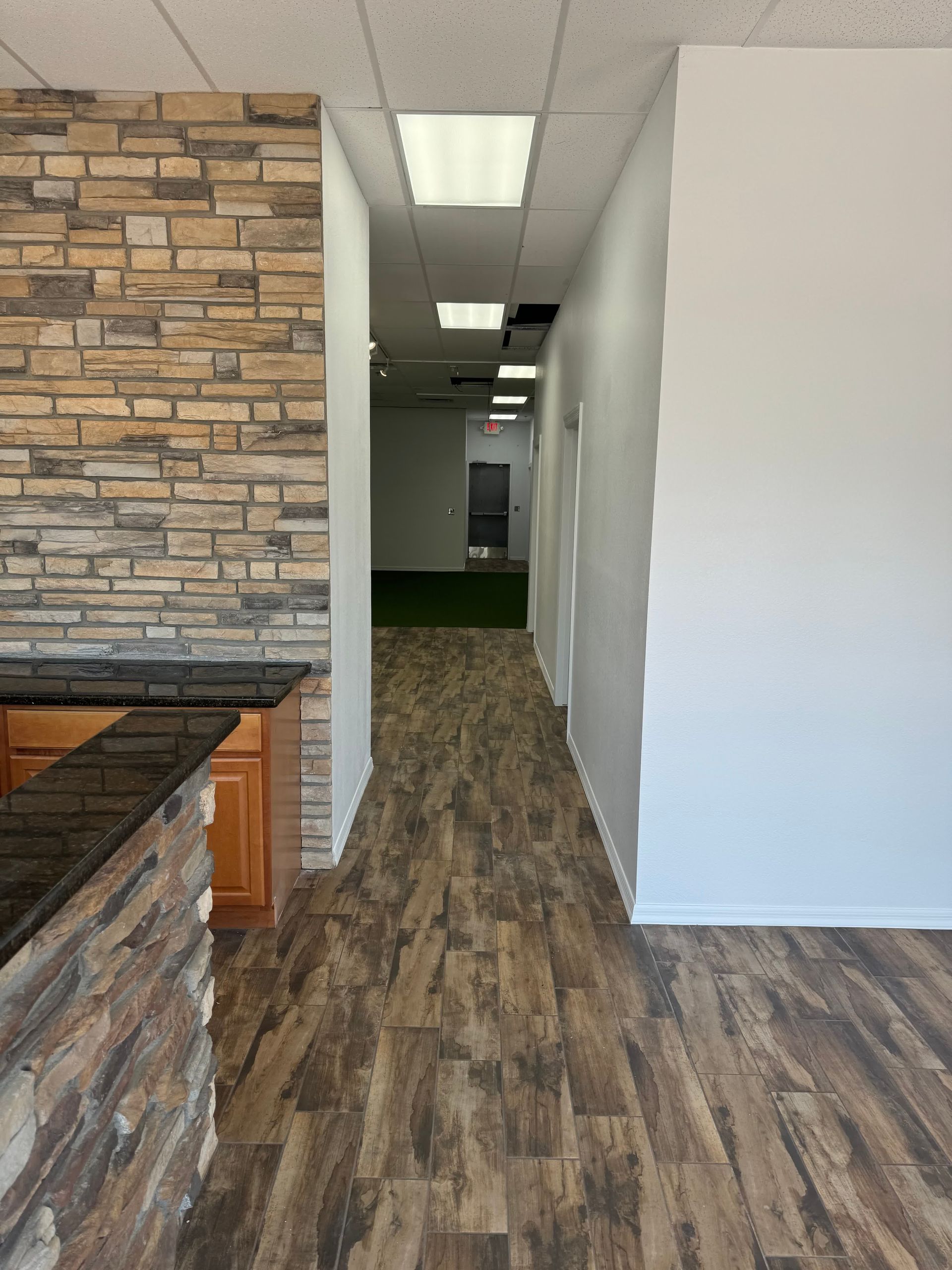 A hallway with wood floors and a brick wall