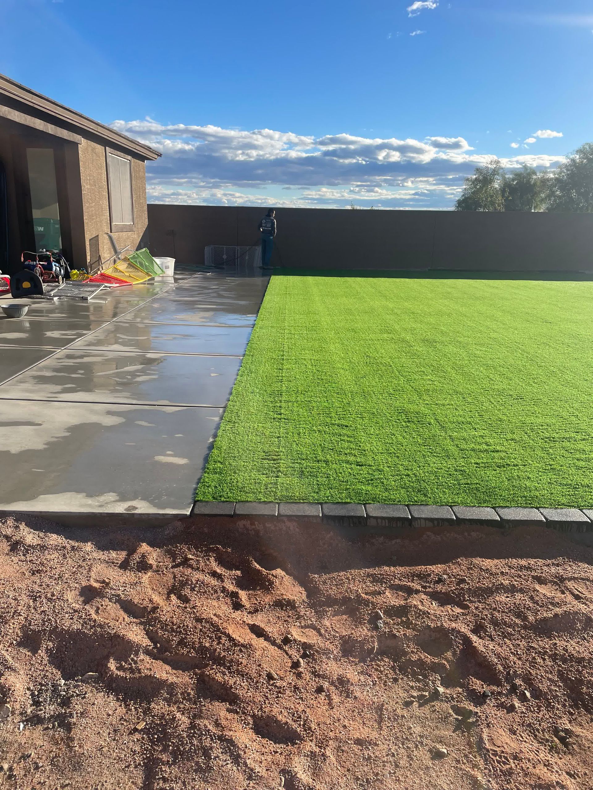 A lawn with a concrete walkway leading to it and a house in the background.