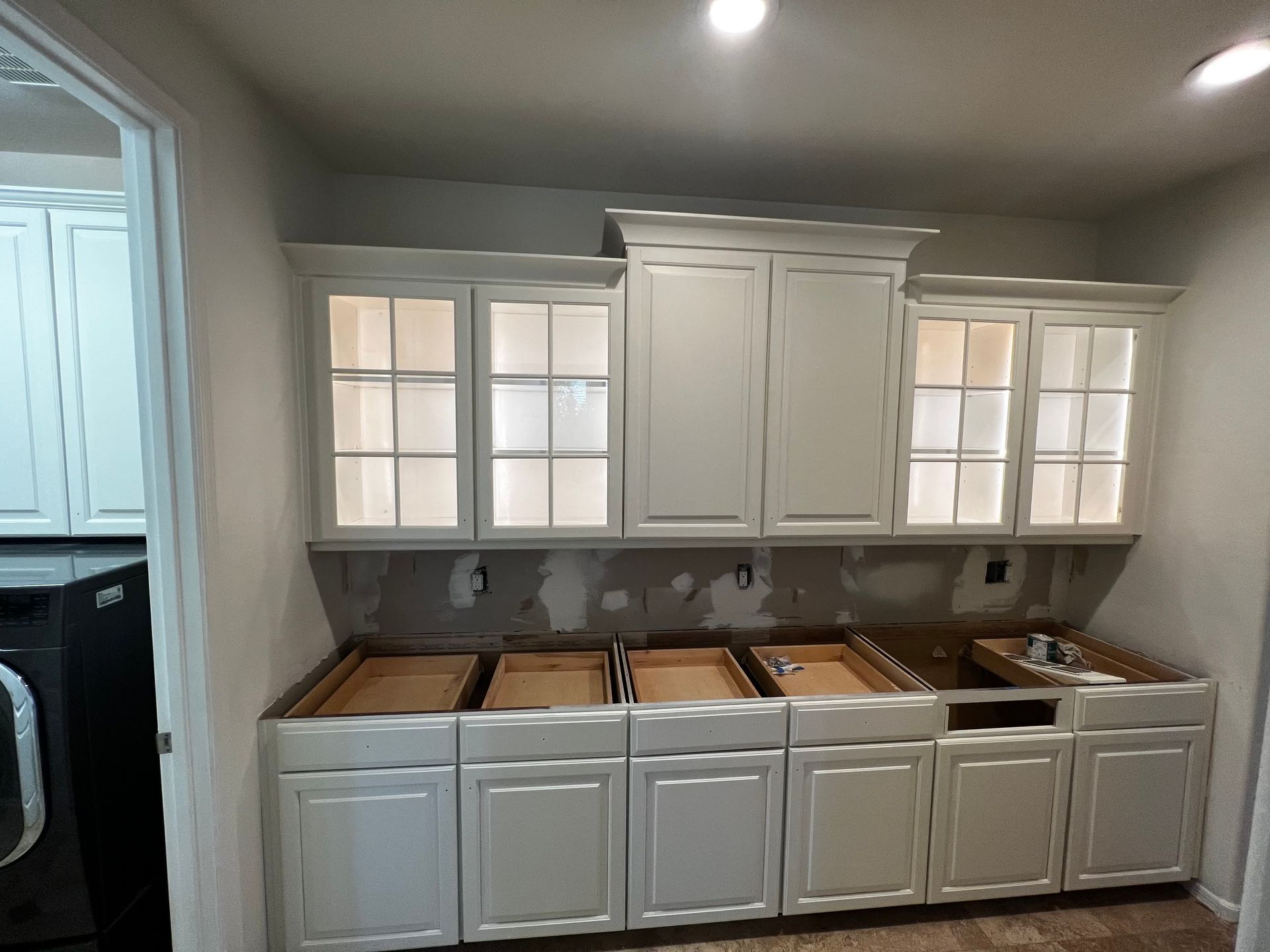 A kitchen with white cabinets and a sink under construction.