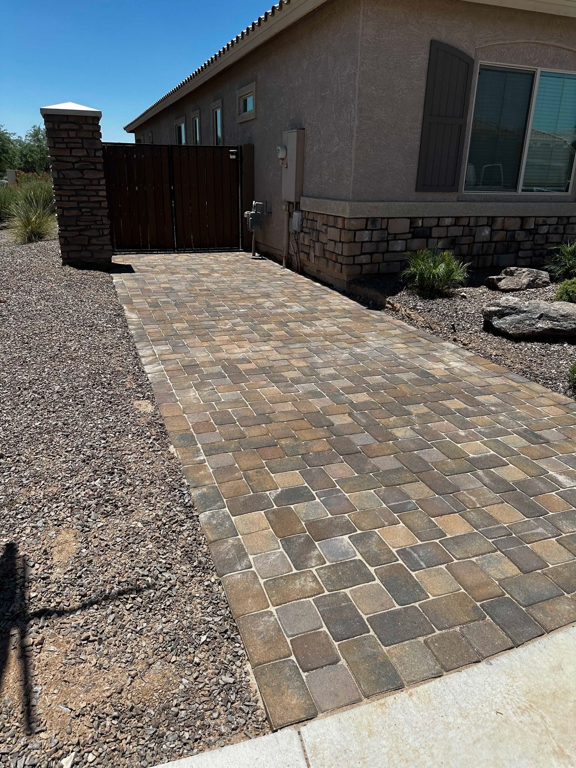 A brick walkway leading to a house with a wooden gate