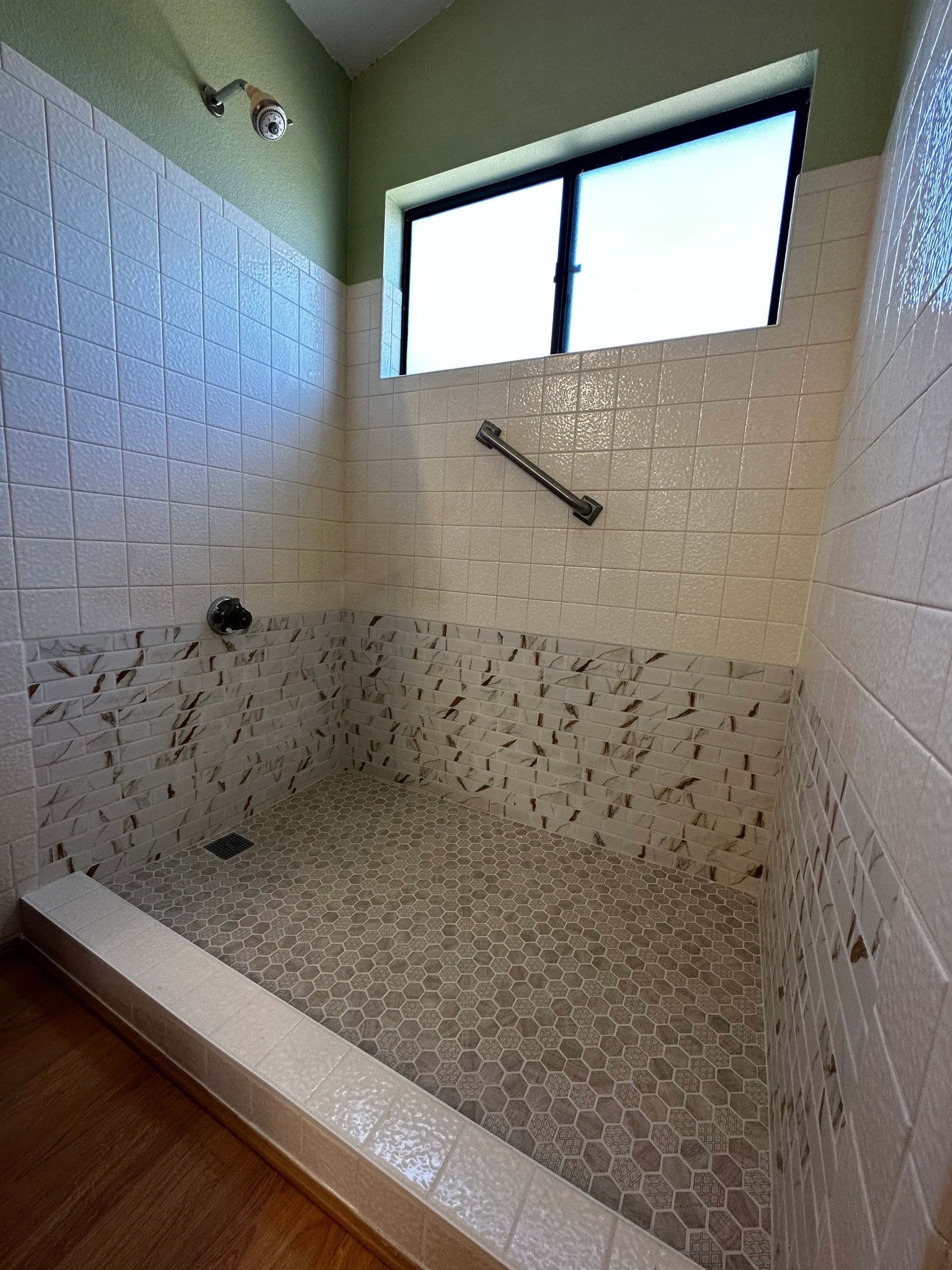 A bathroom with a large shower and a window