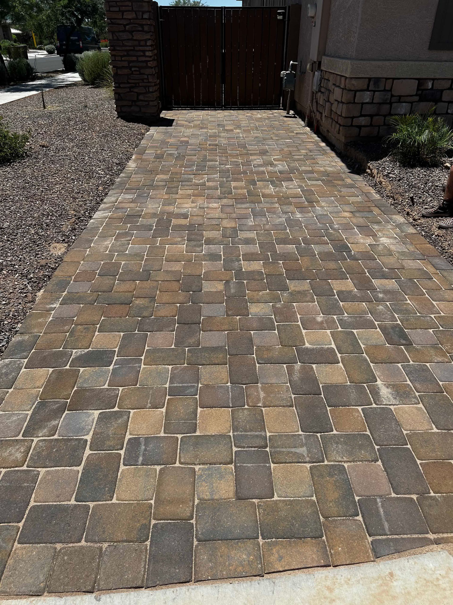 A brick walkway leading to a wooden gate in front of a house.