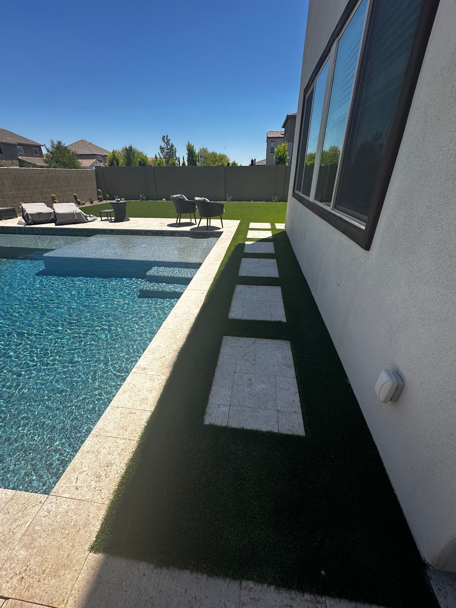 There is a swimming pool in the backyard of a house.