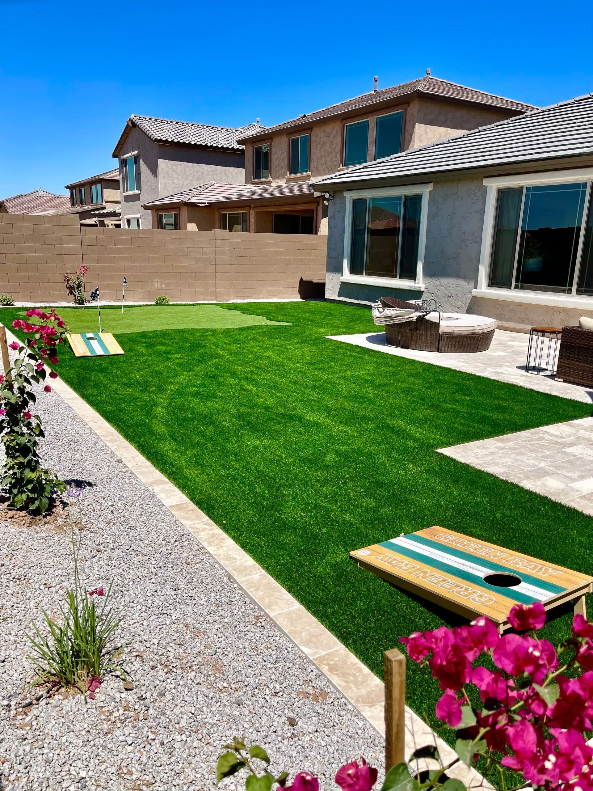 A backyard with a lot of grass and flowers and a house in the background.