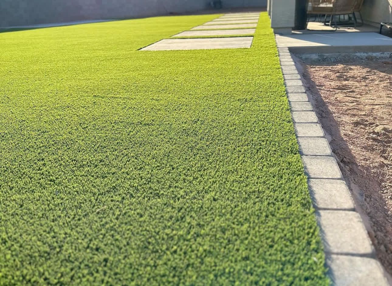 A lush green lawn with a walkway leading to it.