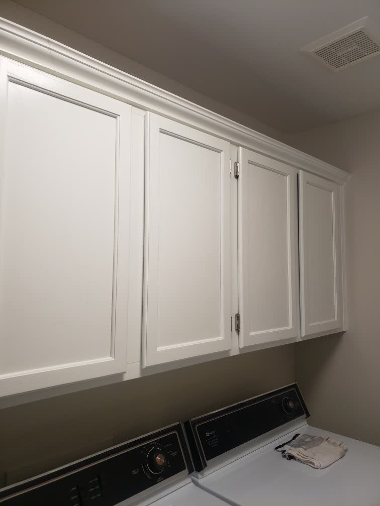 A laundry room with white cabinets and a washer and dryer