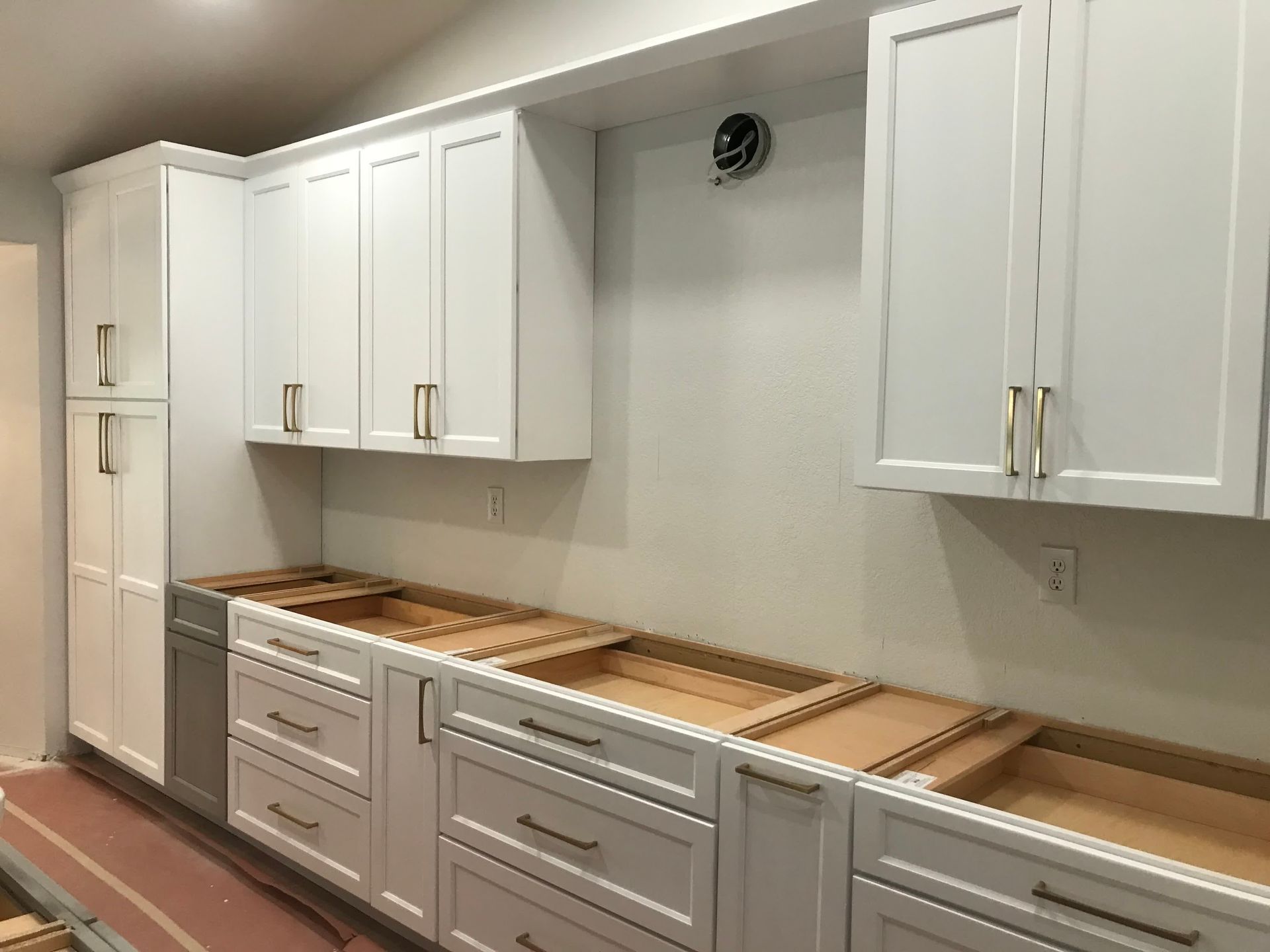 A kitchen with white cabinets and drawers is being built.