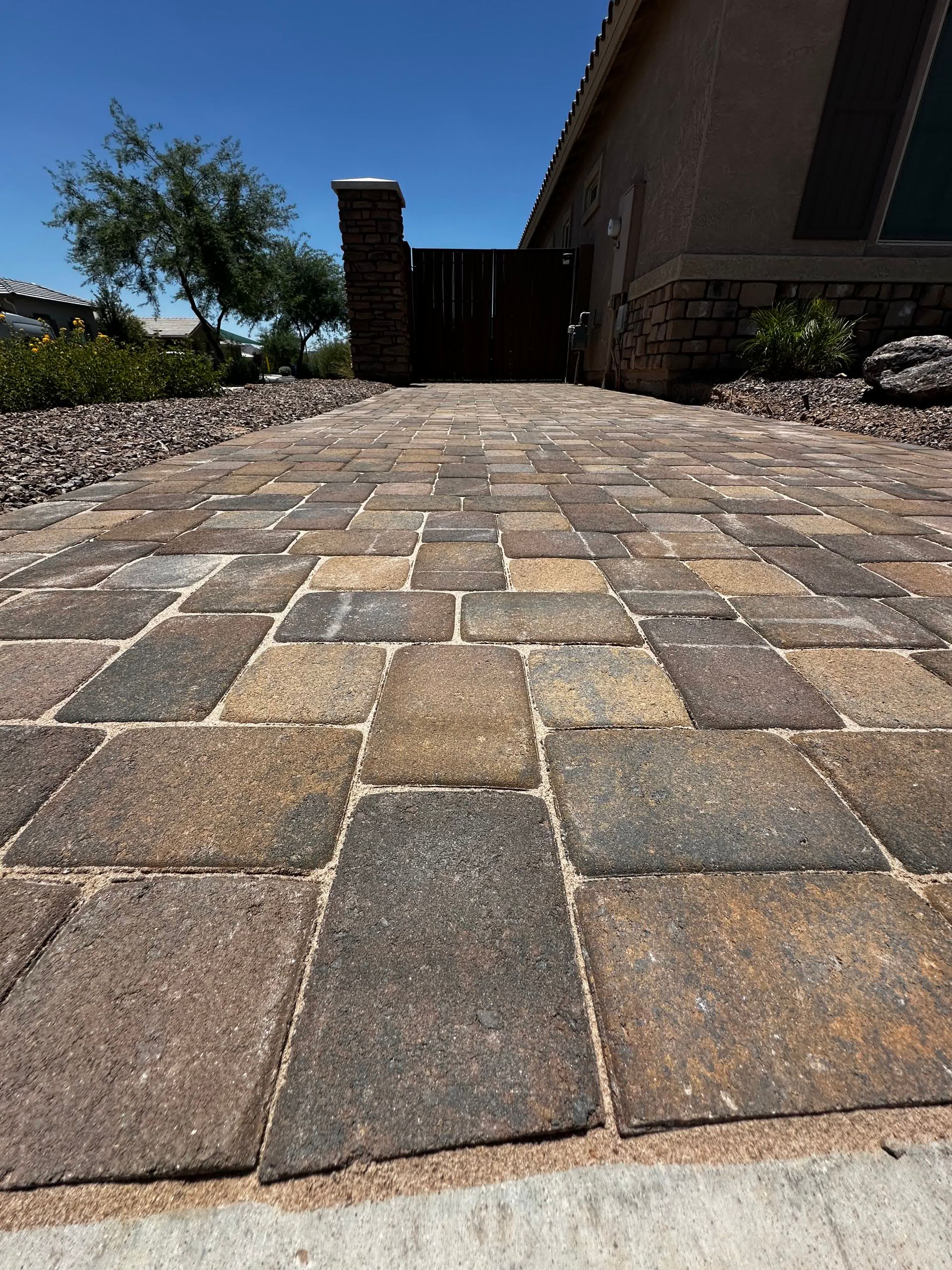 A brick walkway leading to a house on a sunny day.