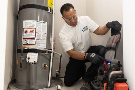 A man is working on a water heater in a room.