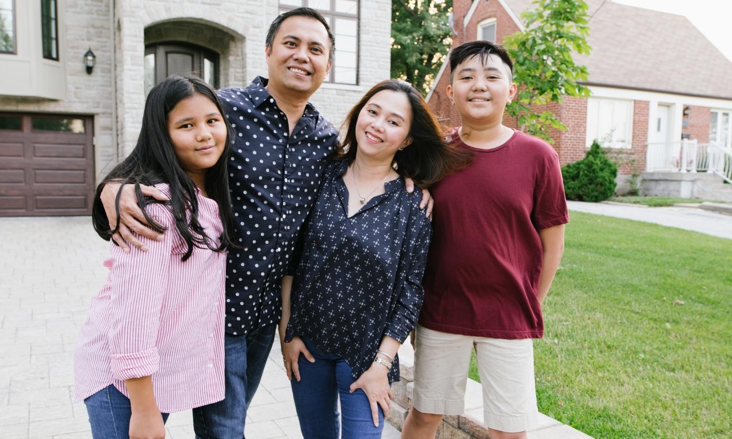 Smiling family in front of house