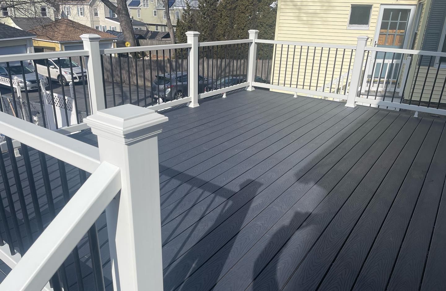 A deck with a white railing and a shadow of a person on it.