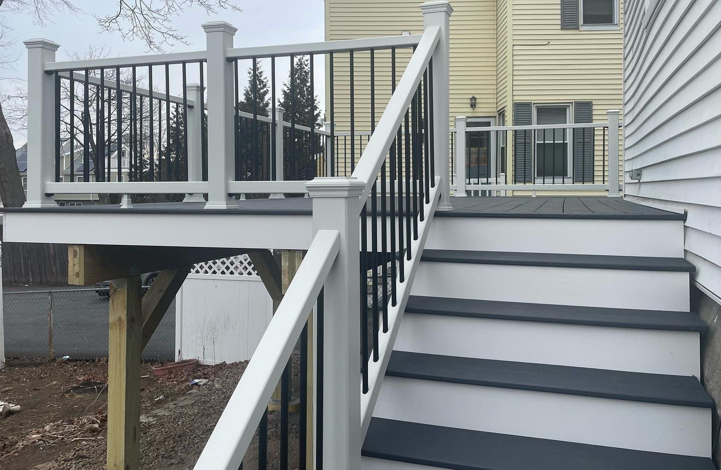 A deck with stairs leading up to it and a house in the background.