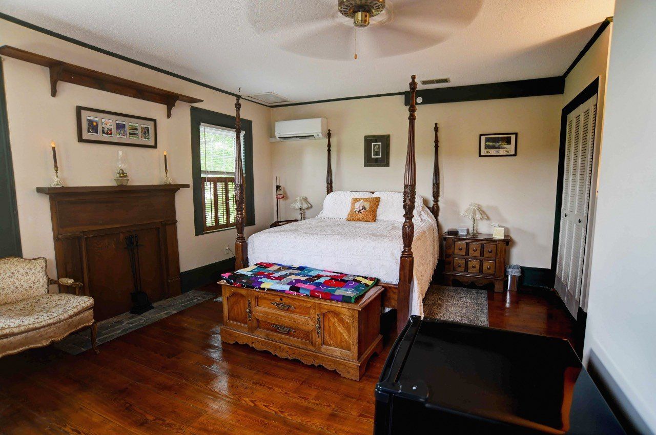 A bedroom with a four poster bed and a fireplace.