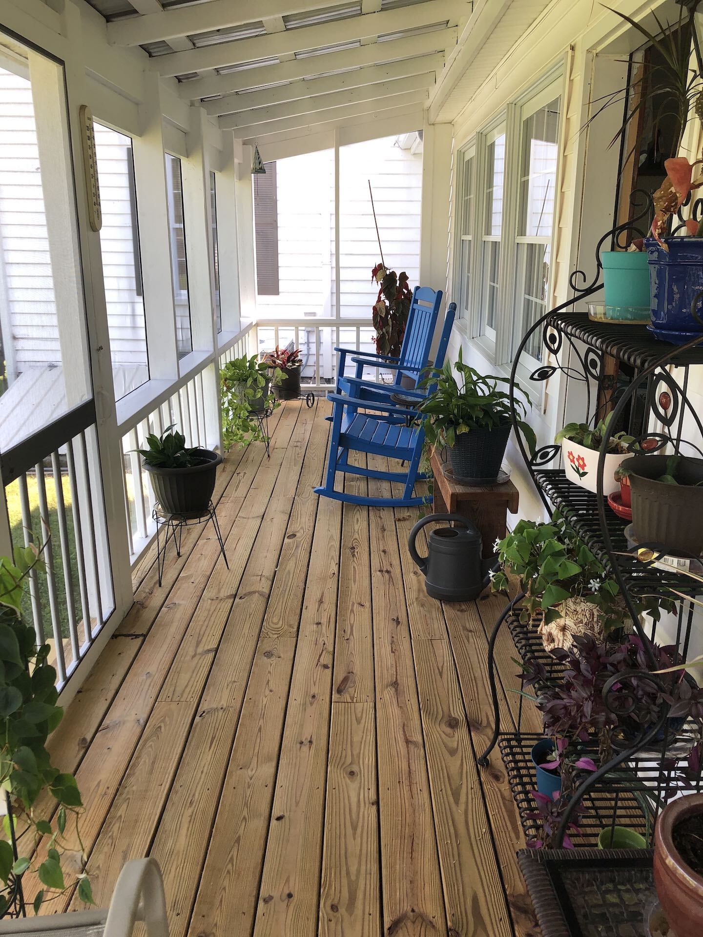 A wooden porch with rocking chairs and potted plants.