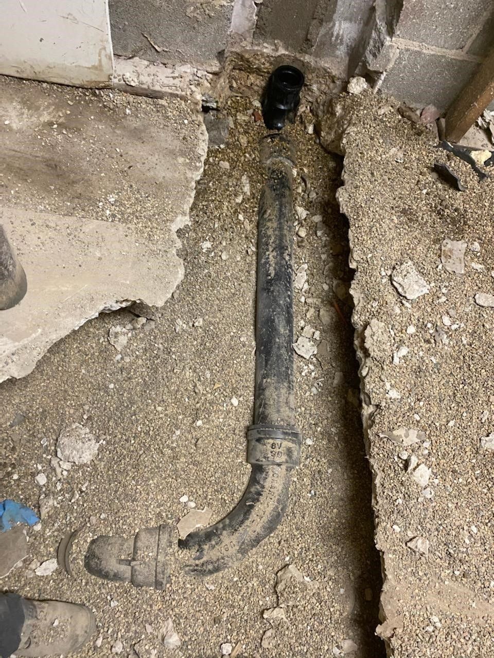 Black plumbing pipe and p-trap in a concrete floor.