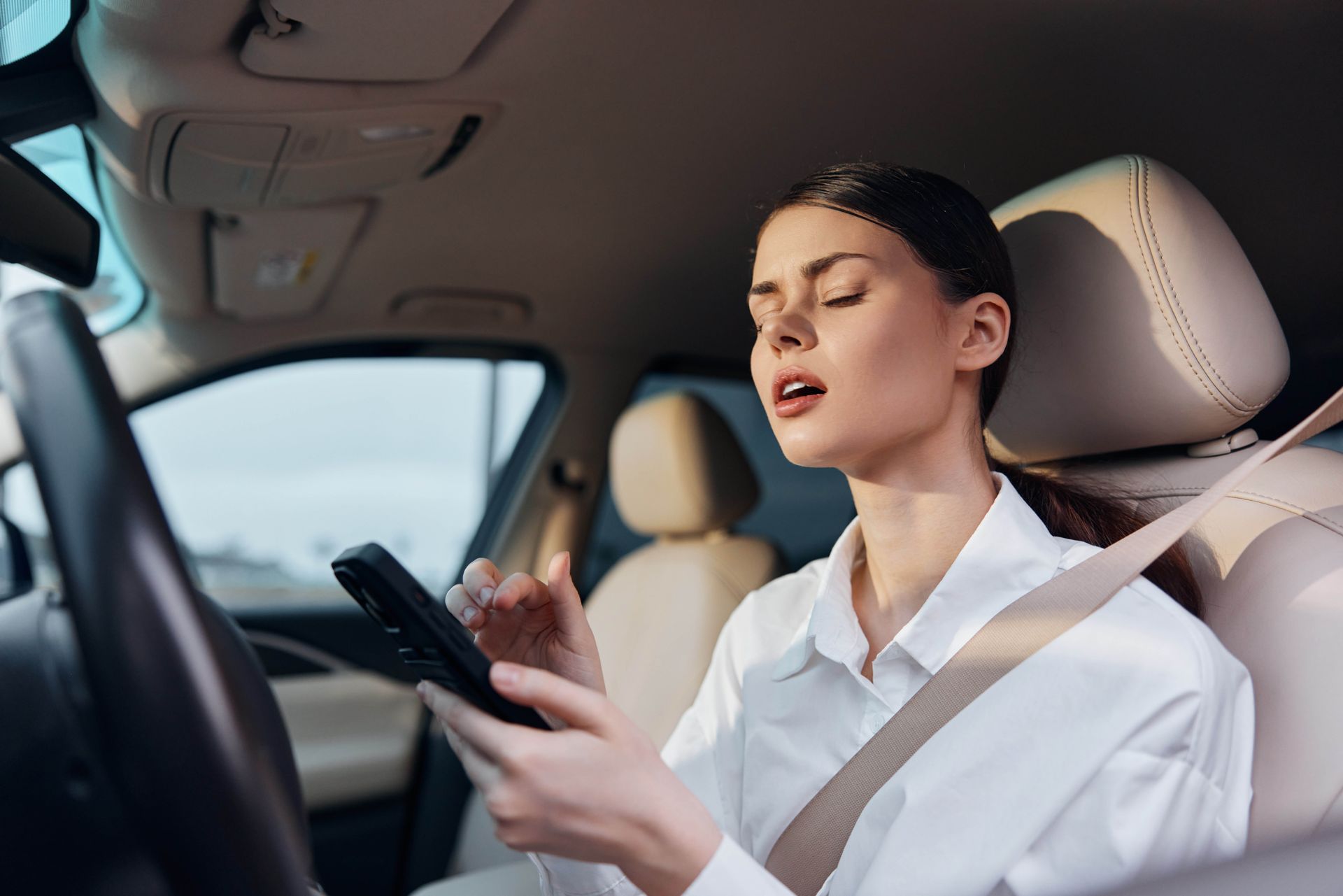 Negligent driving as a distracted driver looks at her phone behind the wheel.