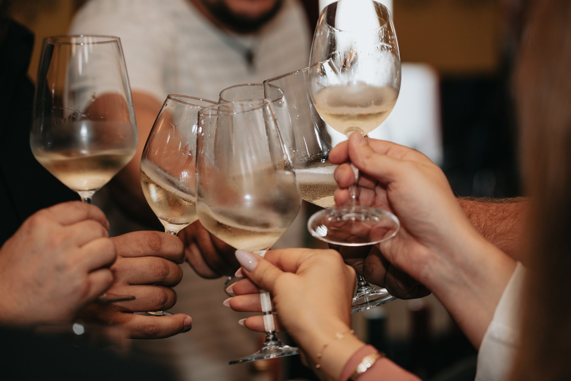Mani che brindano con bicchieri di vino.