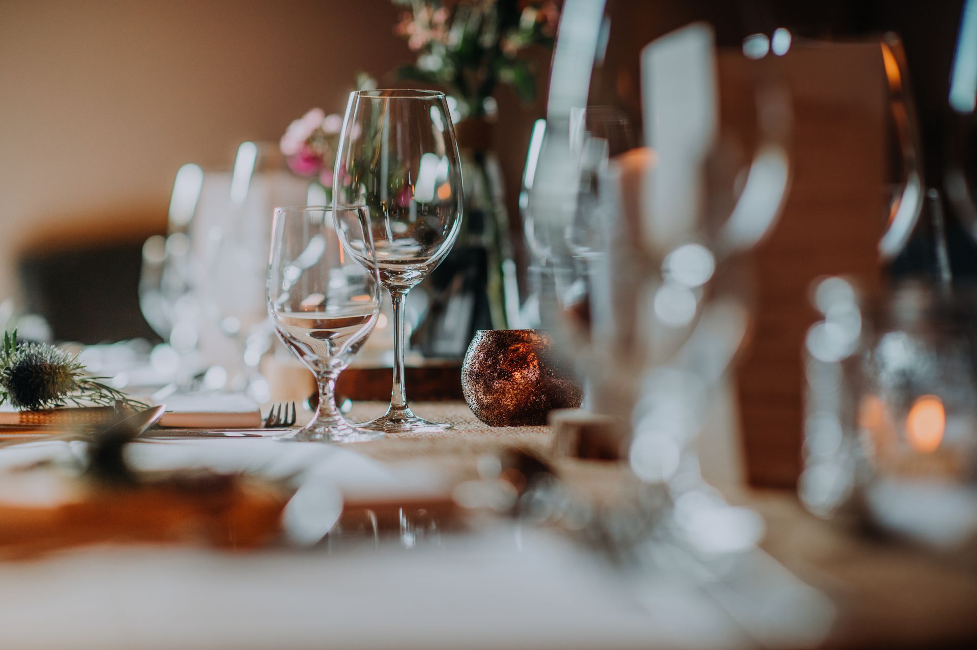Elegante apparecchiatura della tavola con bicchieri da vino, fiori e un'atmosfera calda e invitante.