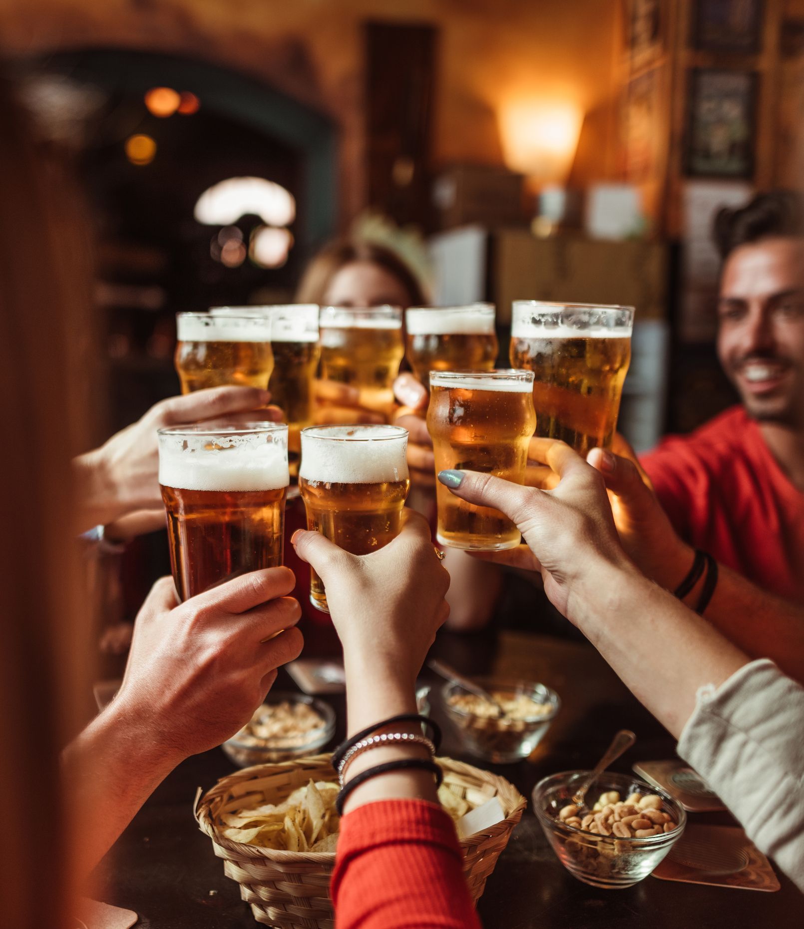 Persone che brindano con boccali di birra in un pub scarsamente illuminato.