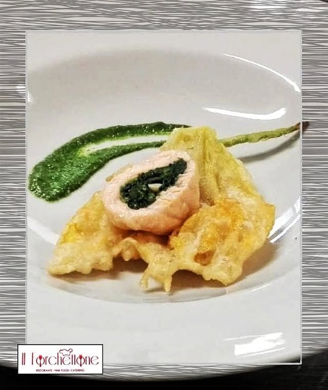 Rotolo di salmone con spinaci, tempura e salsa verde su un piatto bianco.