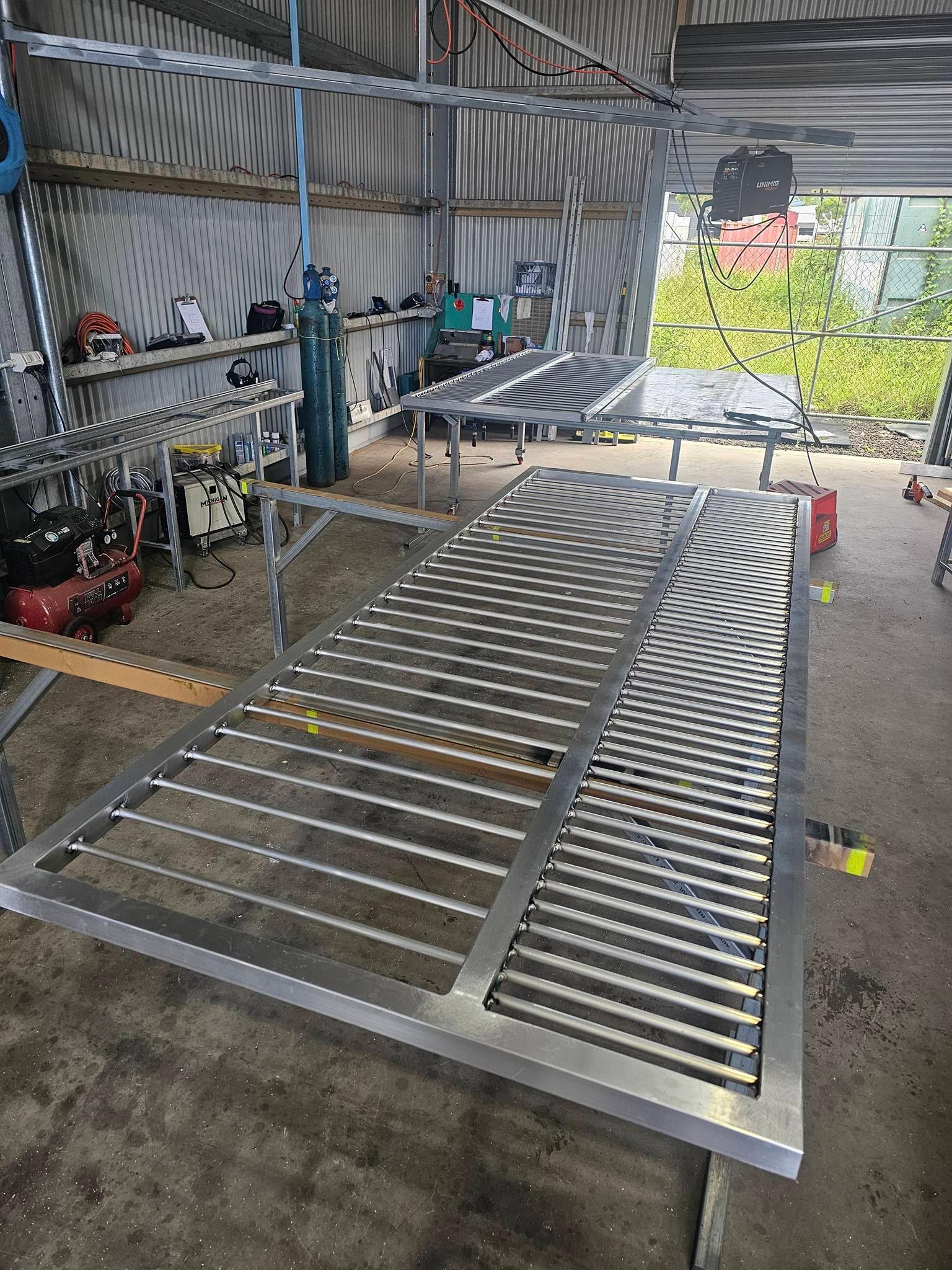Metal bed frame and slatted panels in a workshop, with tools and equipment along the wall.