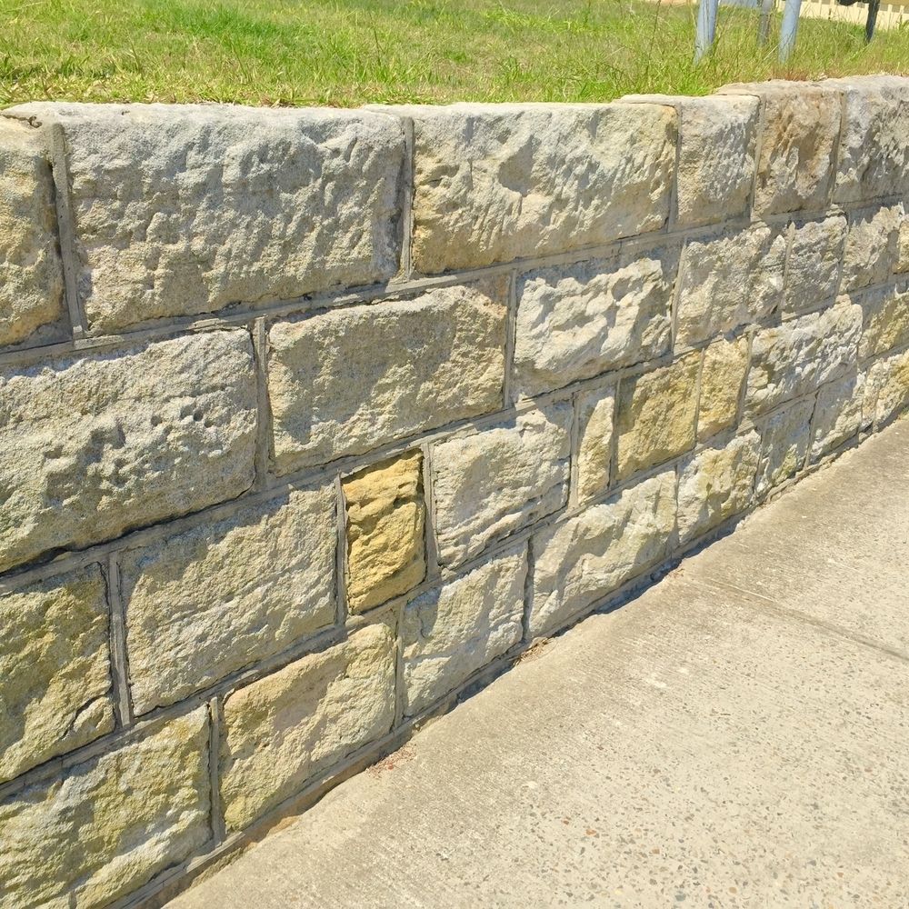Stone Retaining Wall Beside a Concrete Sidewalk — KLS Fencing In Innisfail, QLD