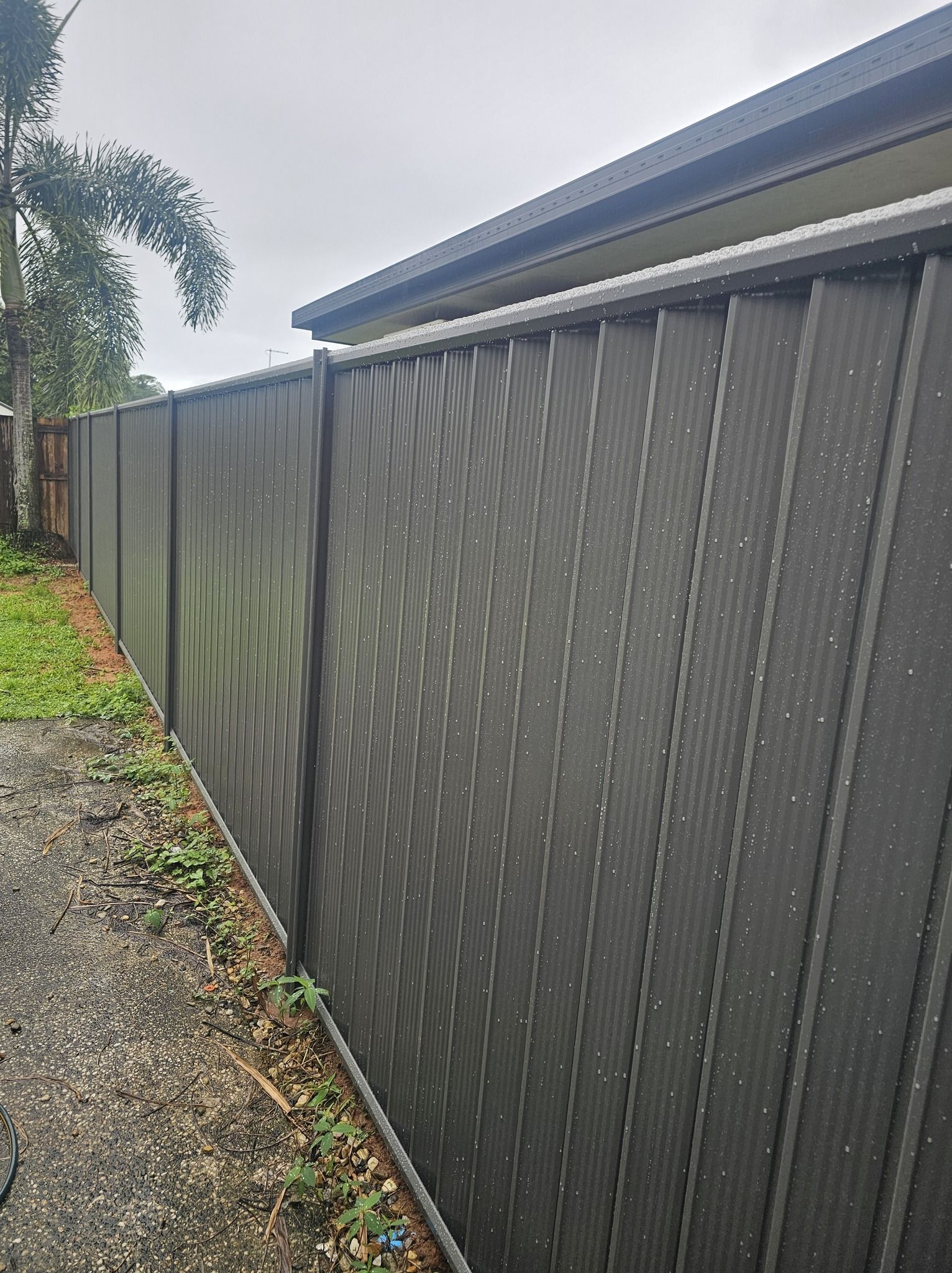 Grey Corrugated Fence Along a Gravel Path — KLS Fencing In Mossman, QLD